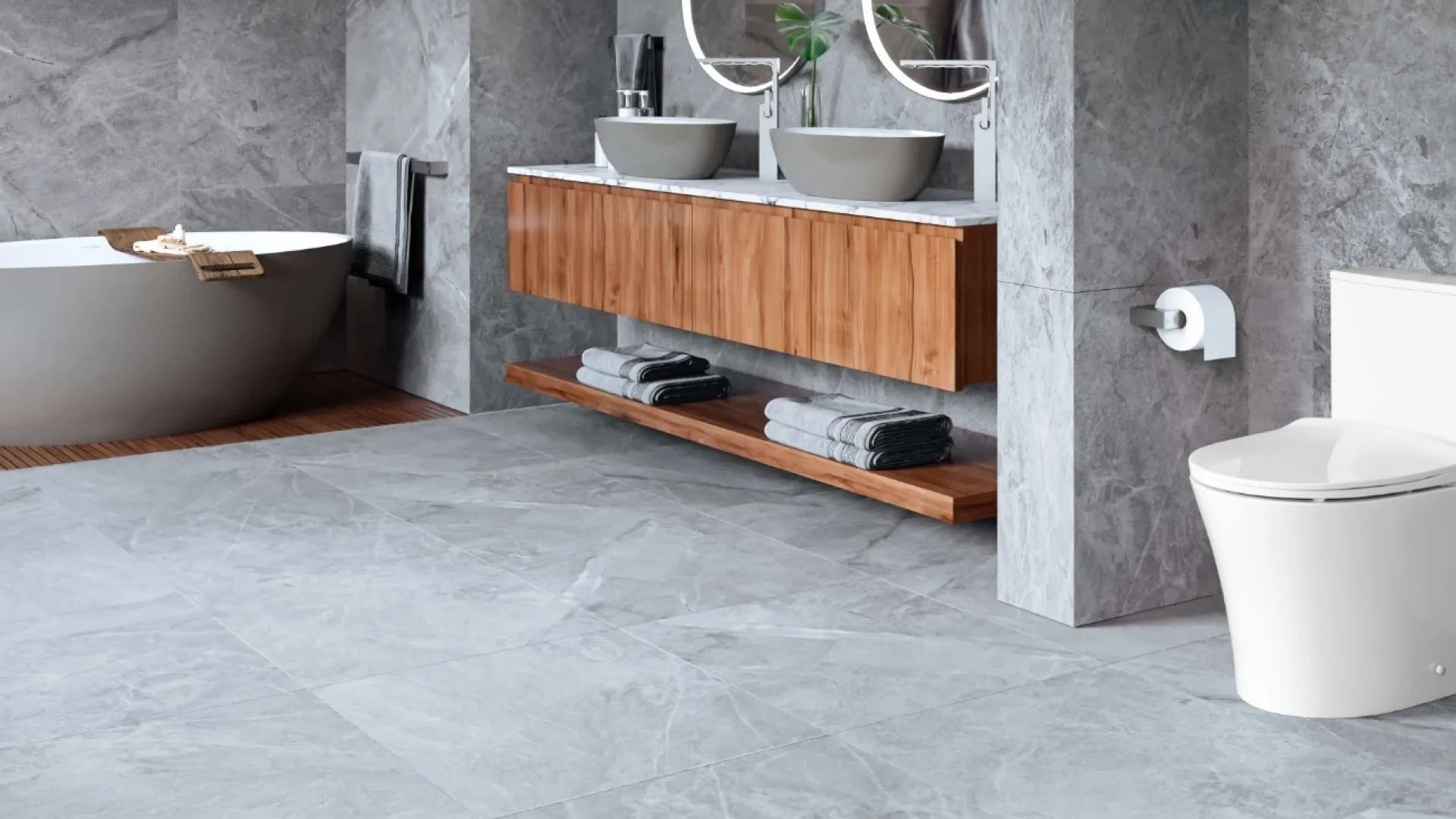 Elegant modern bathroom featuring a freestanding tub, dual sinks, and sleek gray stone accents.