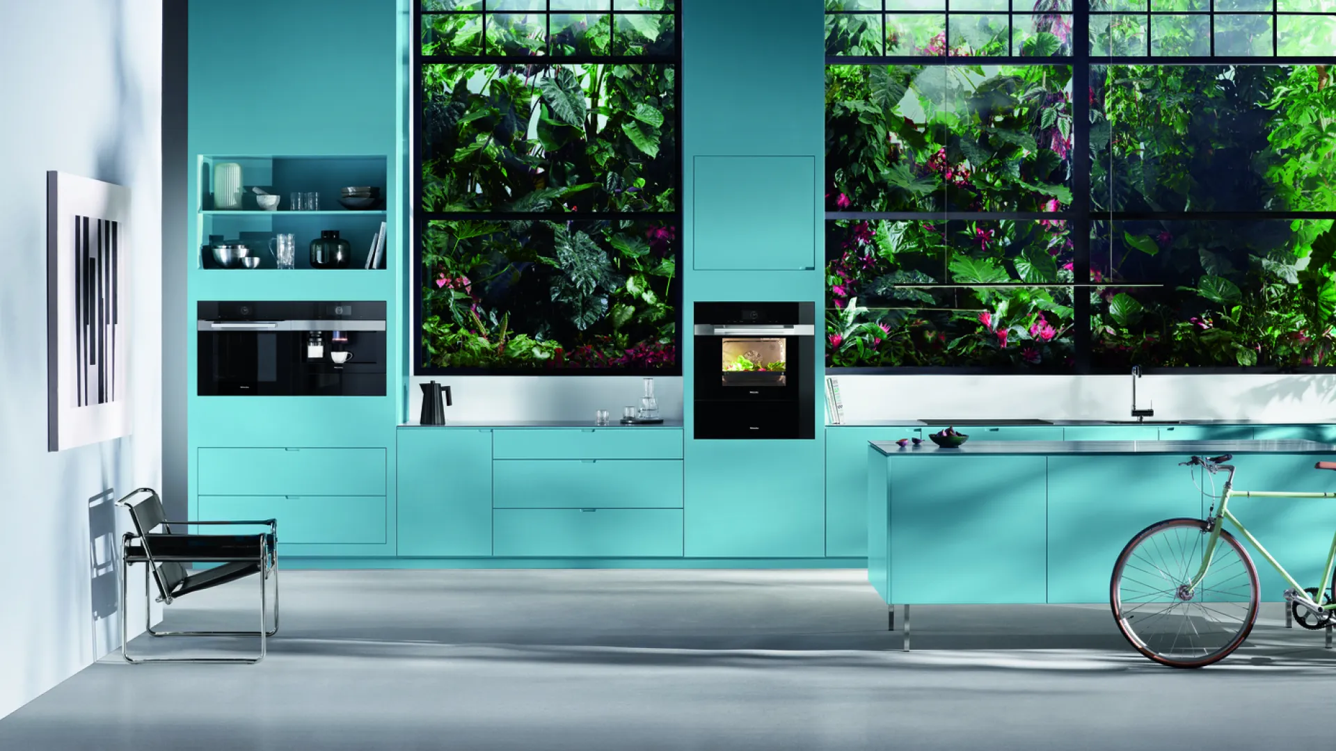 Modern turquoise kitchen with large windows showcasing lush green plants outside and a bicycle inside