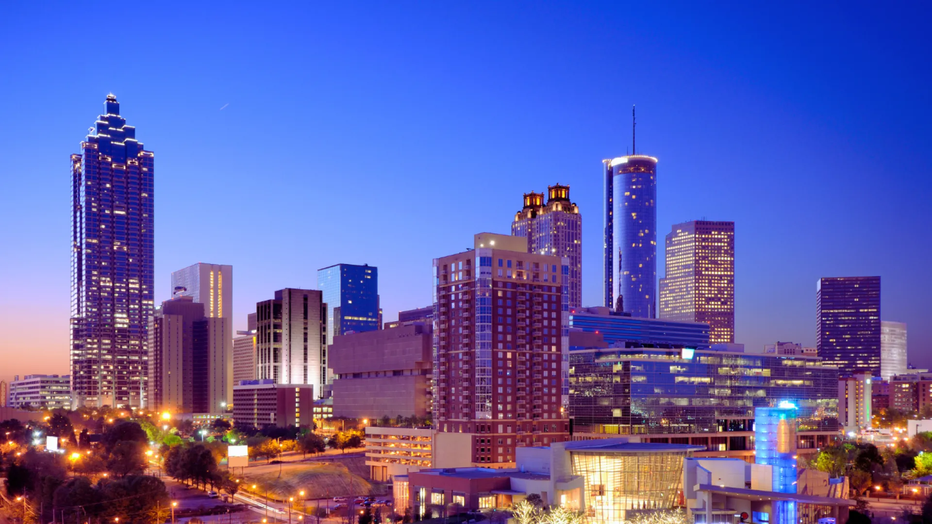 Downtown Atlanta skyline at dusk with illuminated skyscrapers and clear blue sky