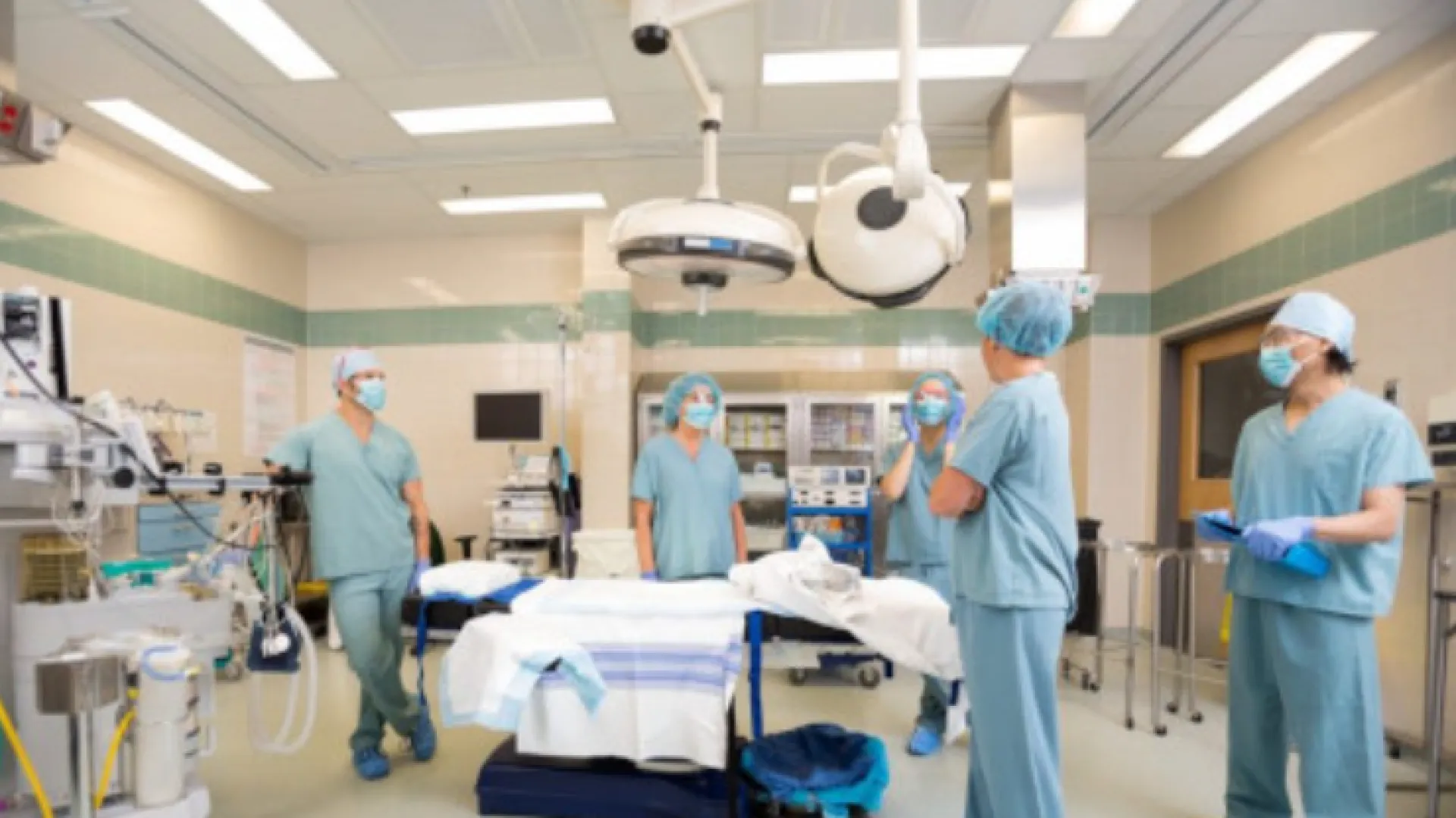 a group of people in surgical scrubs in a room with a table and a bed