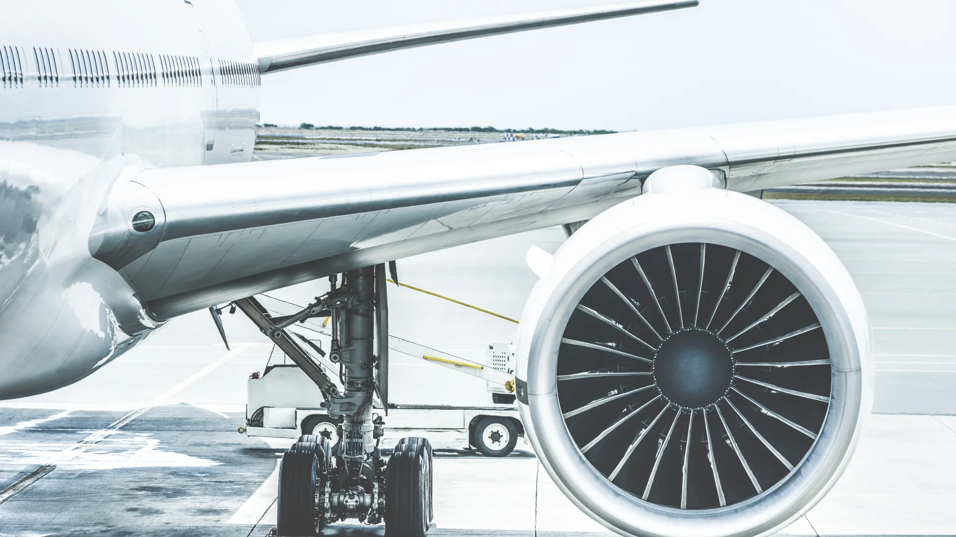 Close-up of airplane engine and landing gear on the tarmac at an airport under daylight conditions