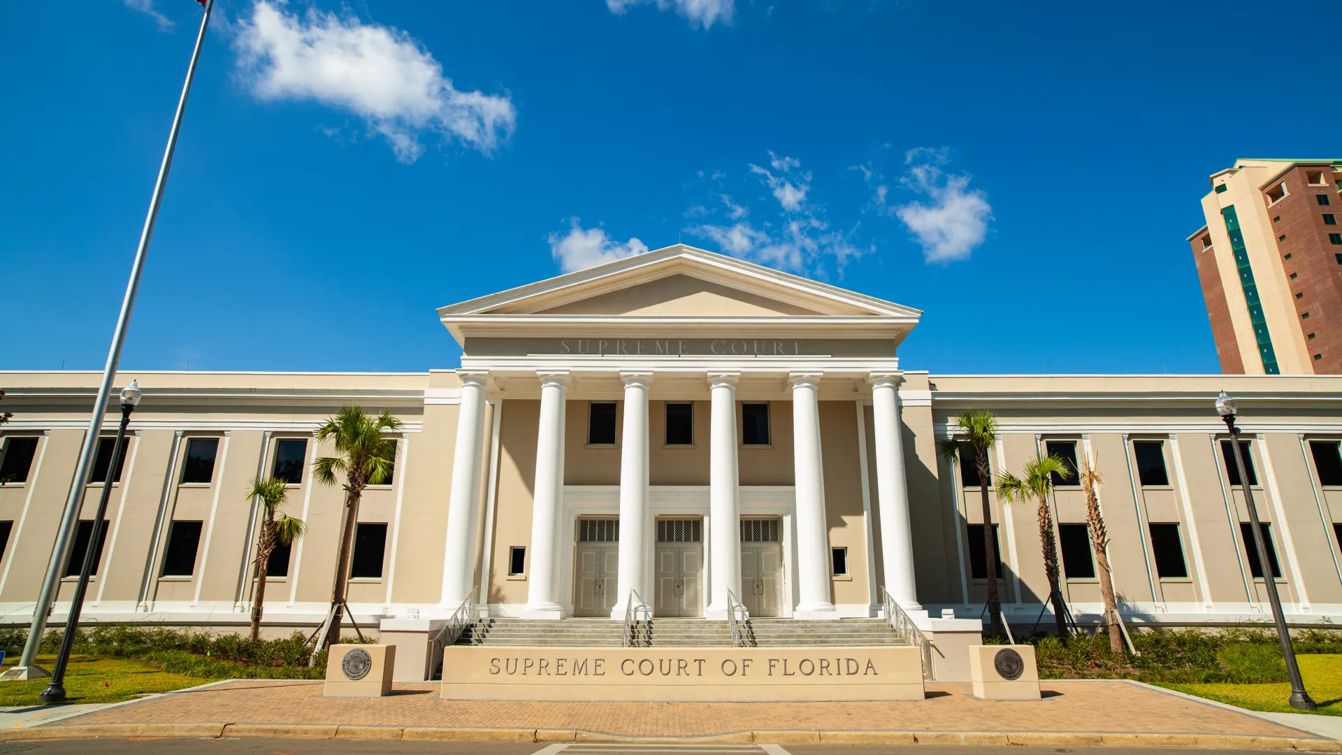 Front view of Supreme Court of Florida building with white columns and clear blue sky background.