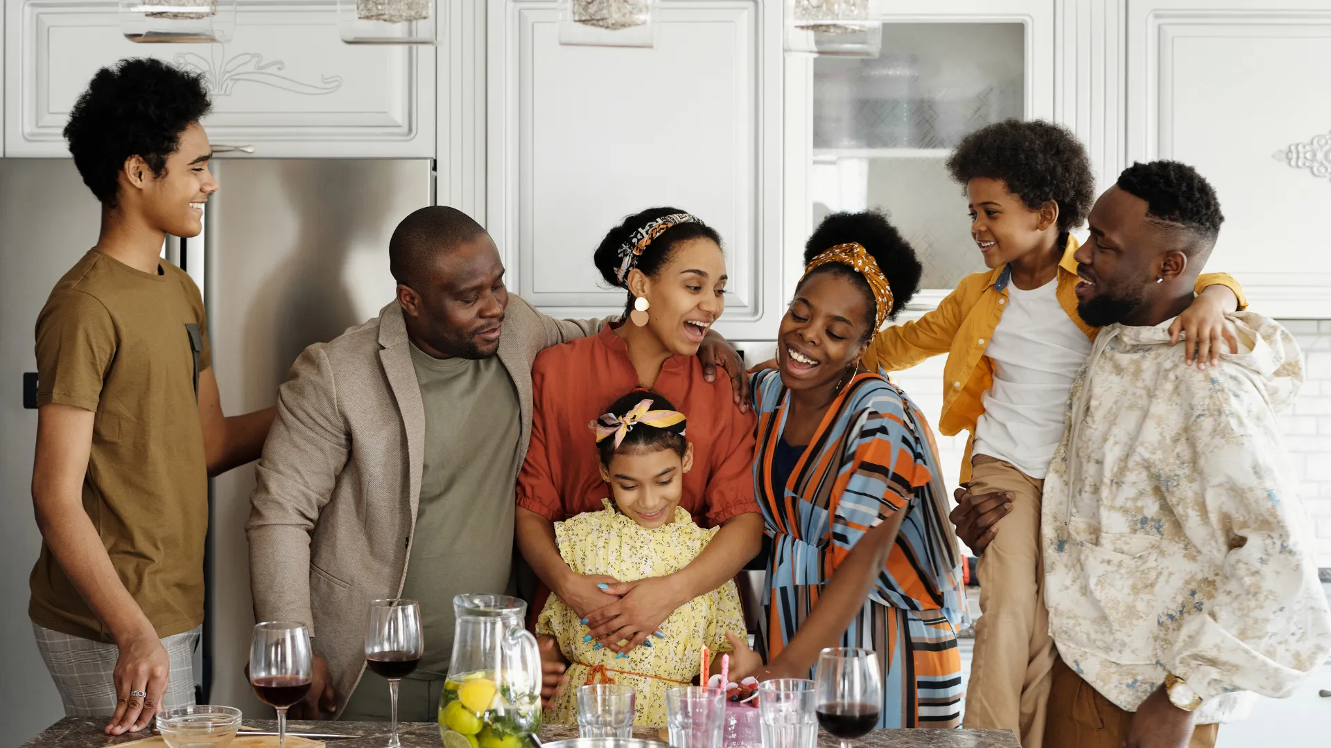 a group of people standing around a table with food and drinks