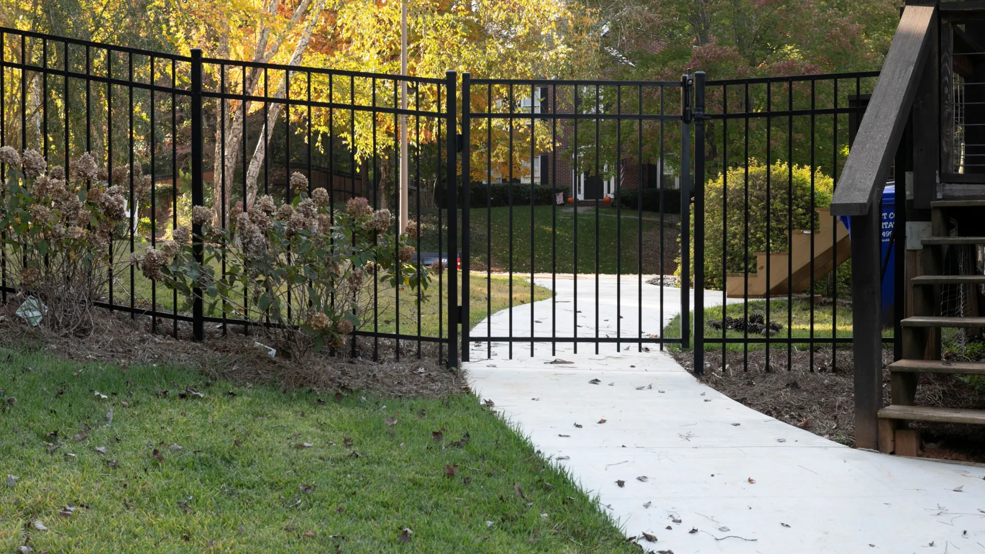 a black gate with a green lawn and trees in the background