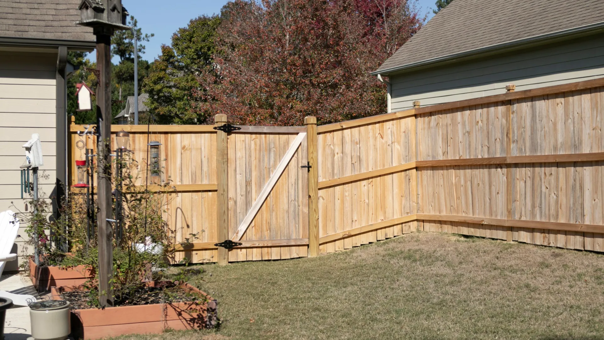 a fenced in yard with a wood gate and a house