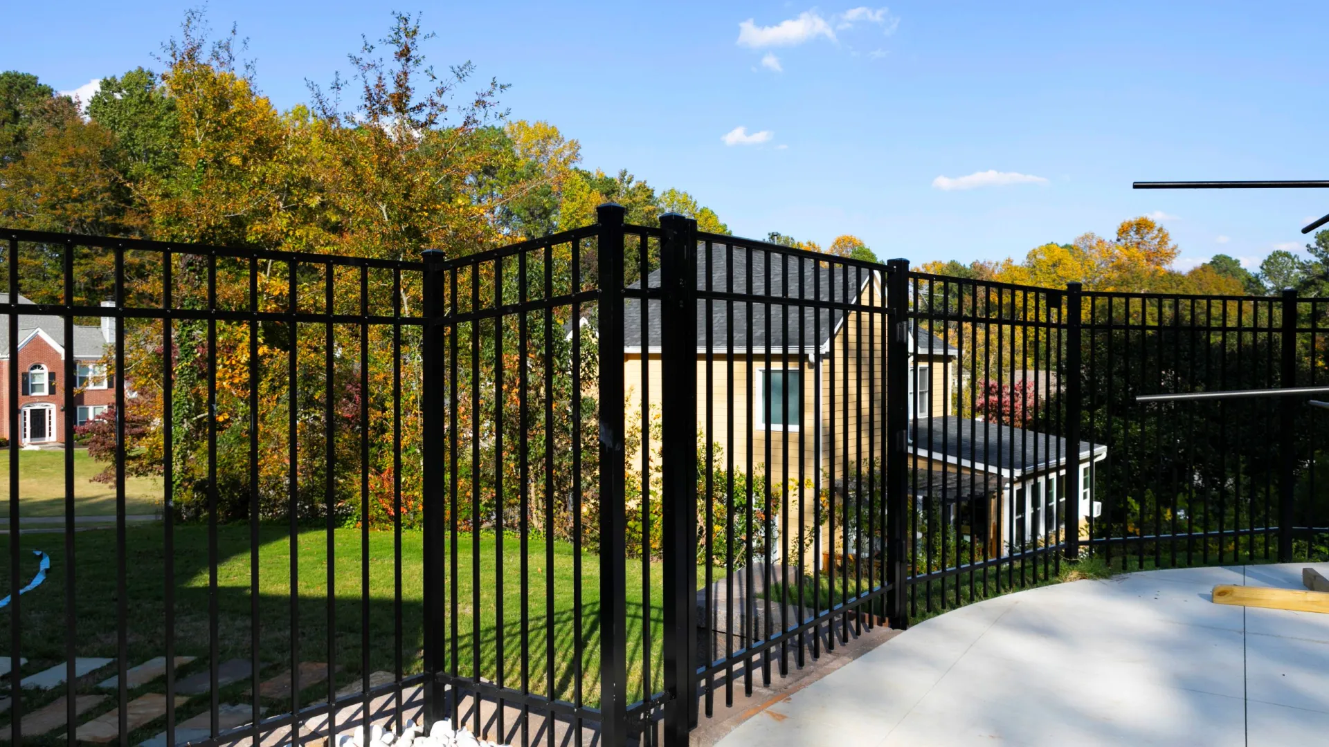 a black gate with a fence around it and trees in the back