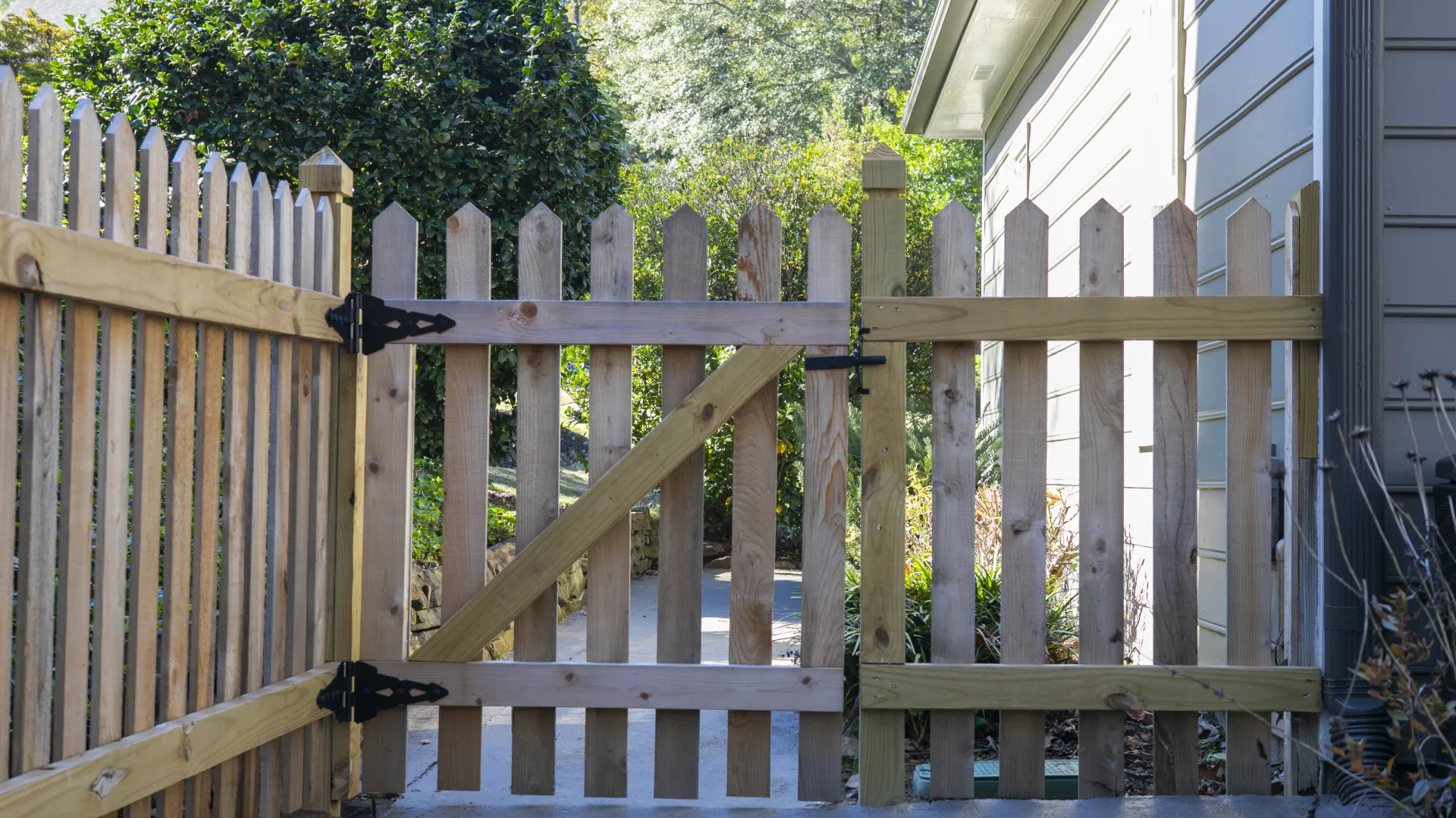 Lush garden gate made of wooden pickets, showcasing a quaint pathway and surrounding greenery.