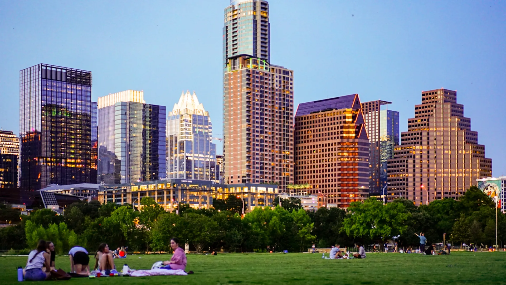 a group of people sitting on the grass in front of austin texas