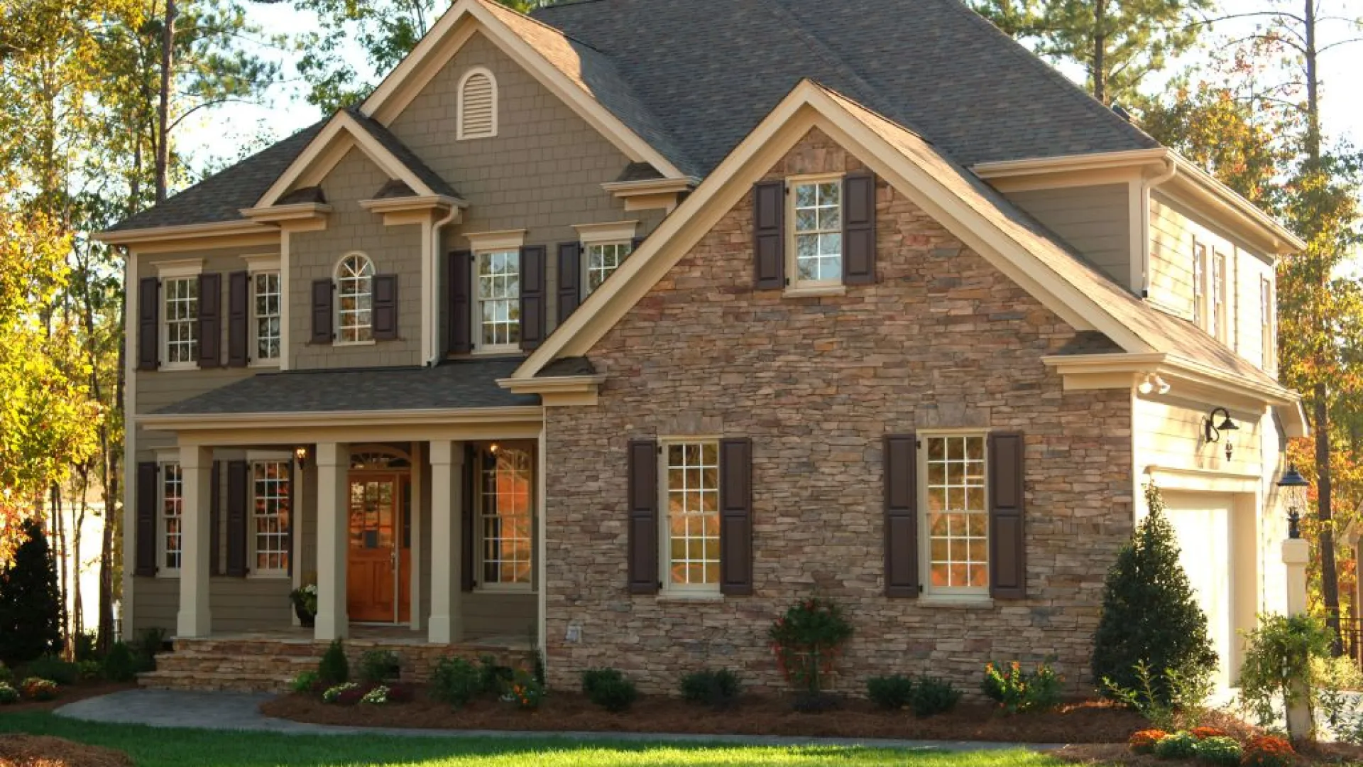White coastal home with wraparound porch and manicured lawn under clear sky in Brookhaven, GA