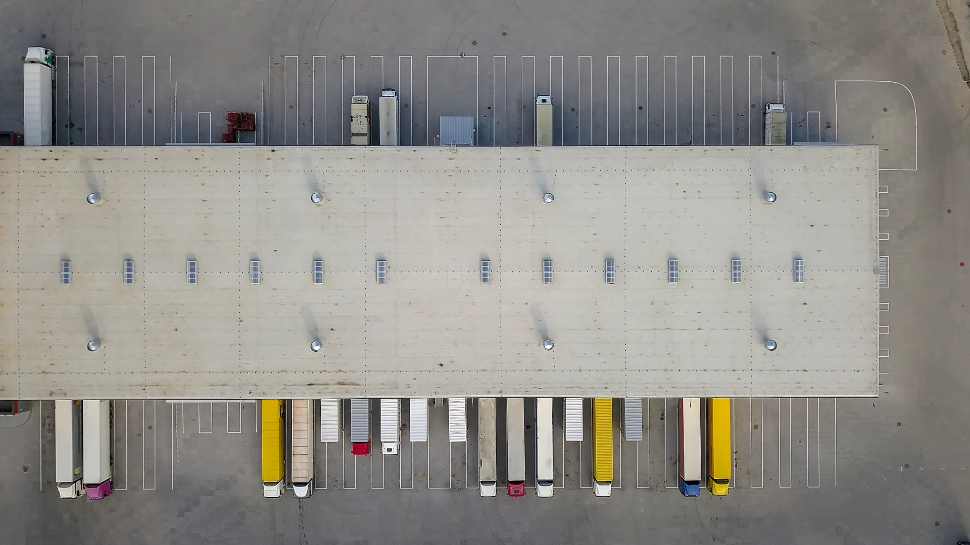 aerial view of large logistics center with several trucks and bays