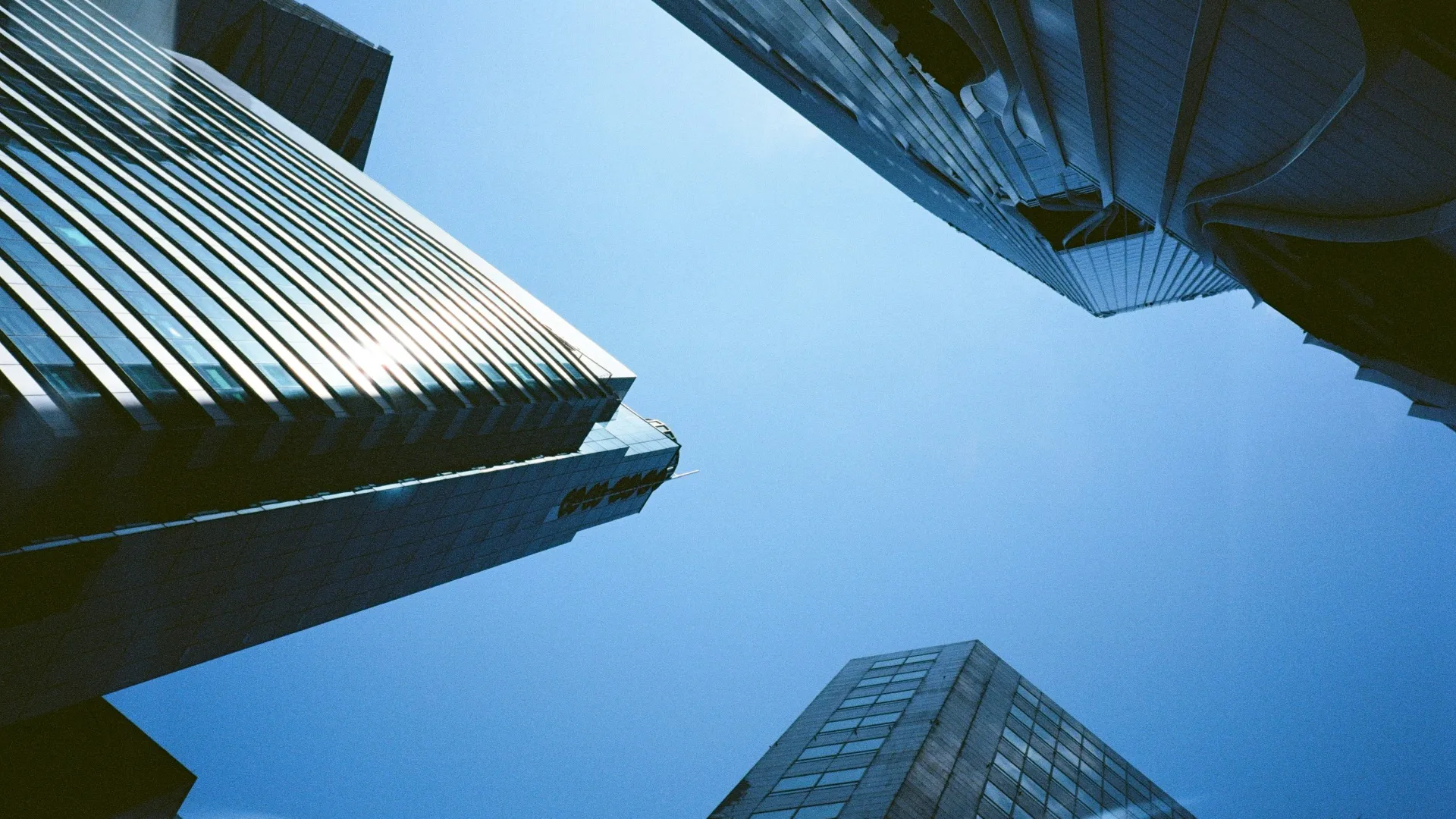 View looking up at modern skyscrapers against a clear blue sky in an urban cityscape.