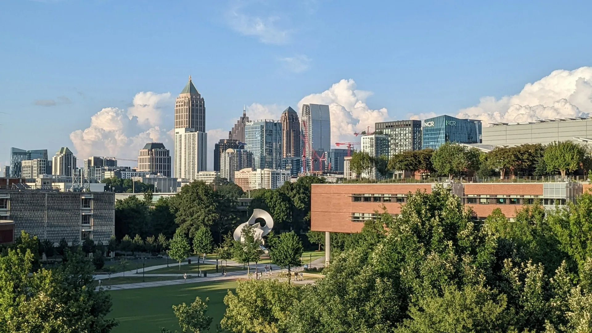 Atlanta skyline with skyscrapers and green parkland in foreground under a blue sky with clouds