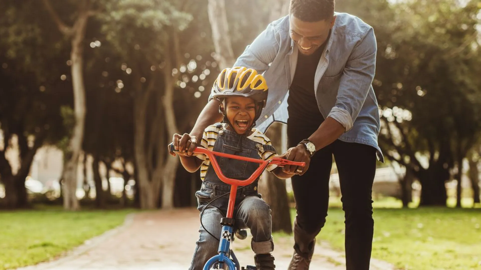 a person pushing a boy on a bike