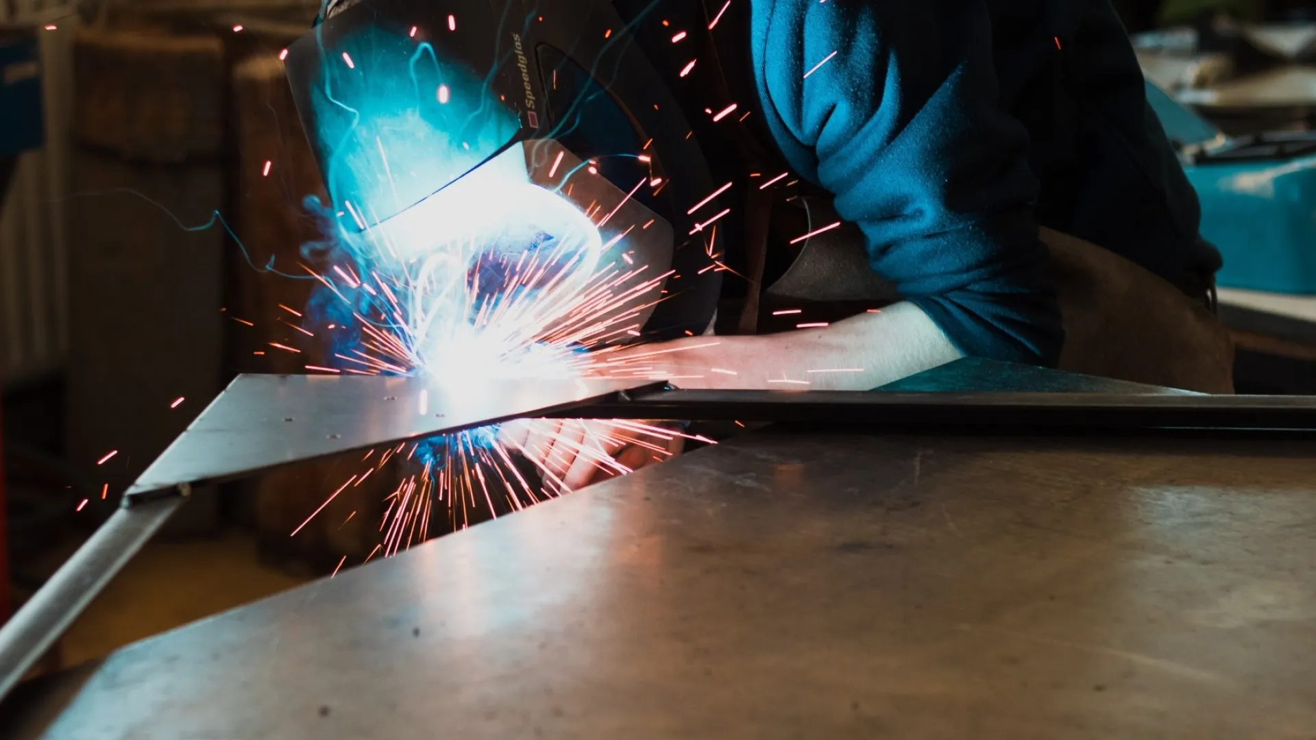 Two construction workers wearing orange helmets installing large glass panels on a building facade.