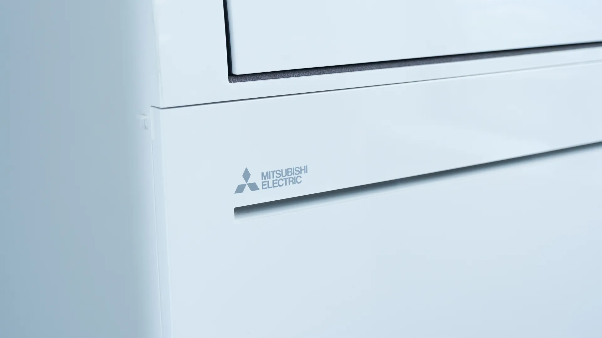 Close-up of a white Mitsubishi Electric air conditioner unit with logo visible on front panel