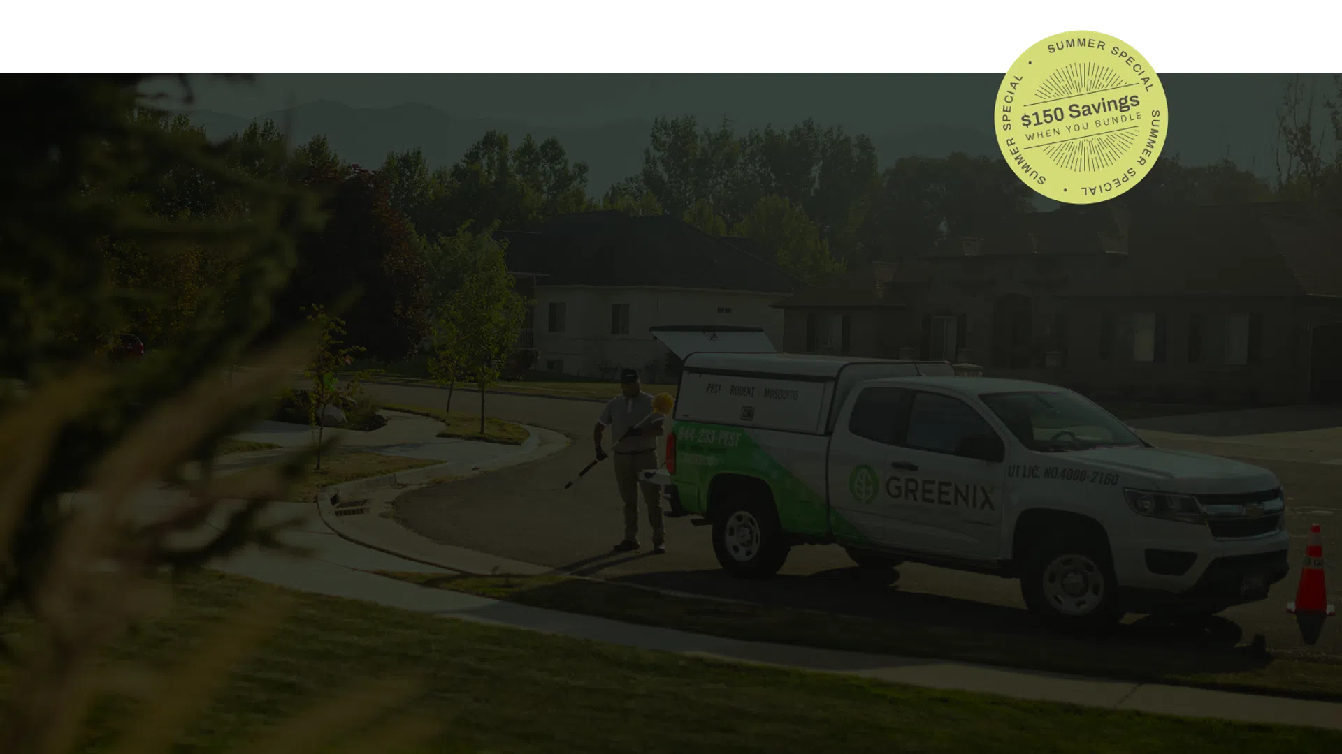 Landscaper working near Greenix service truck on a sunny residential street with trees and houses.