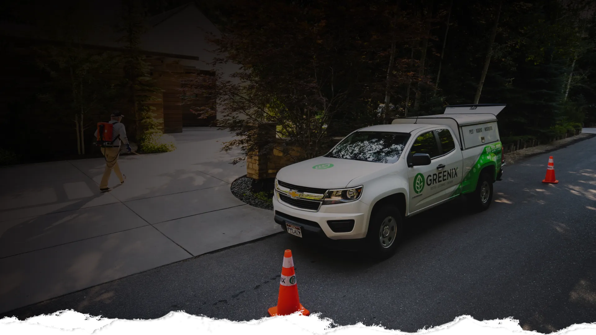 White Greenix service truck parked on a suburban street near orange cones and a worker walking toward a house.