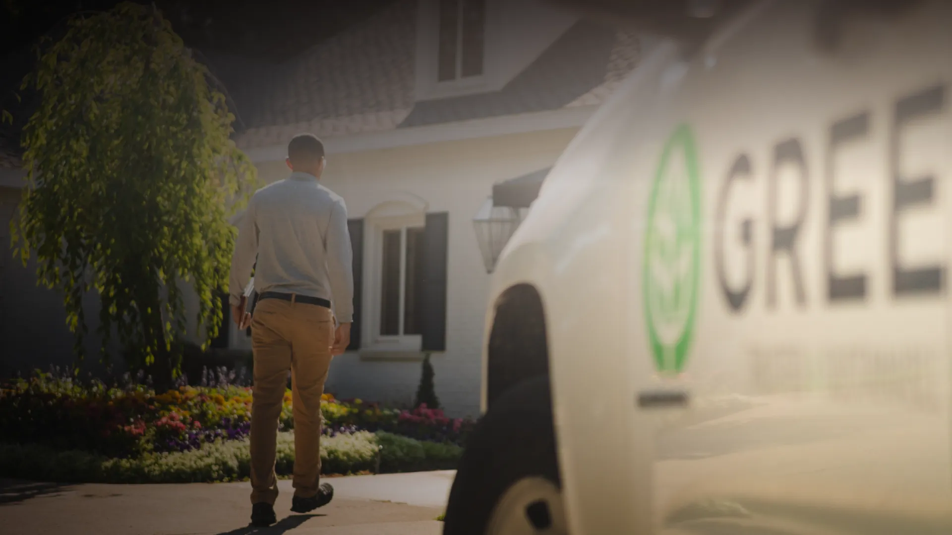 a Greenix truck and employee walking towards a house