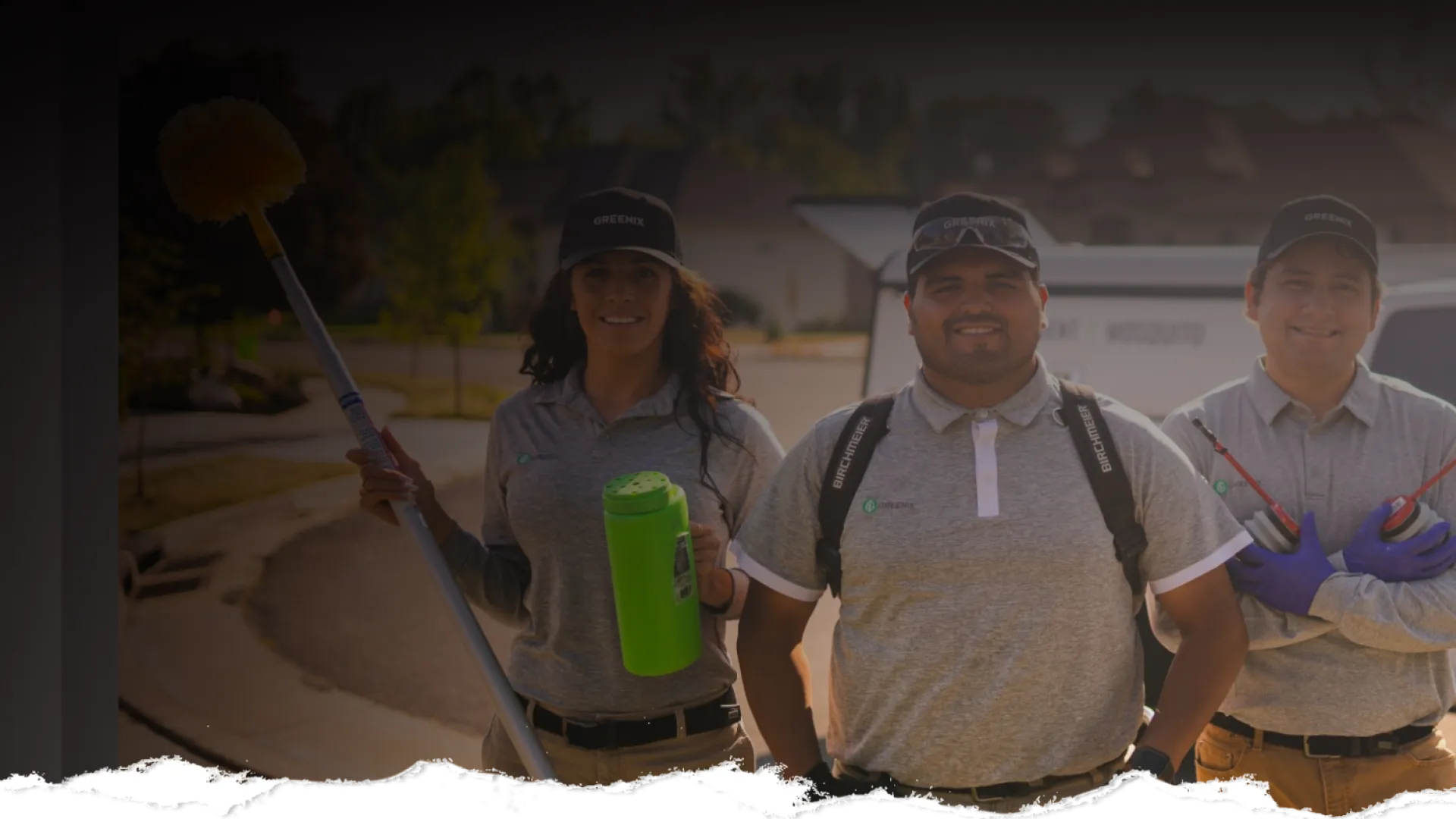 Three pest control technicians in uniform with equipment standing outdoors on a sunny residential street.