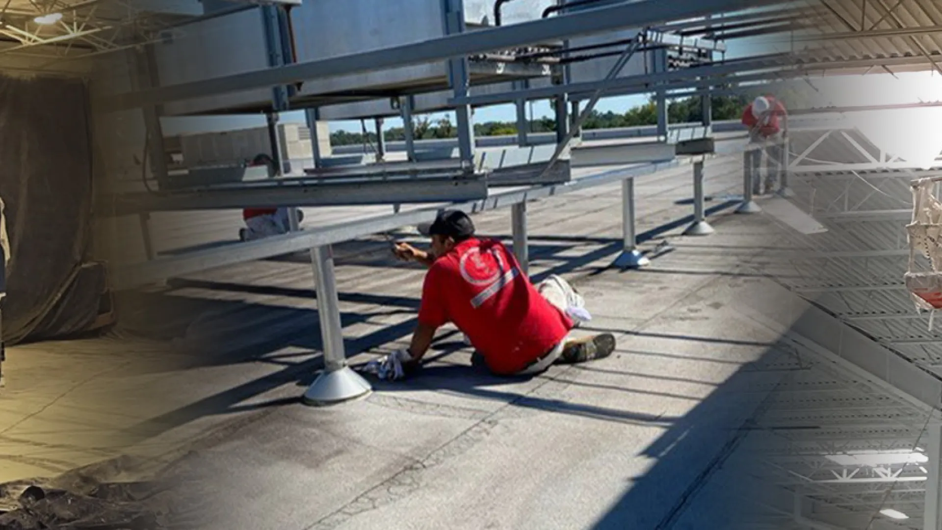 Worker in red shirt painting metal beams indoors using a lift and kneeling tools under bright industrial lighting.