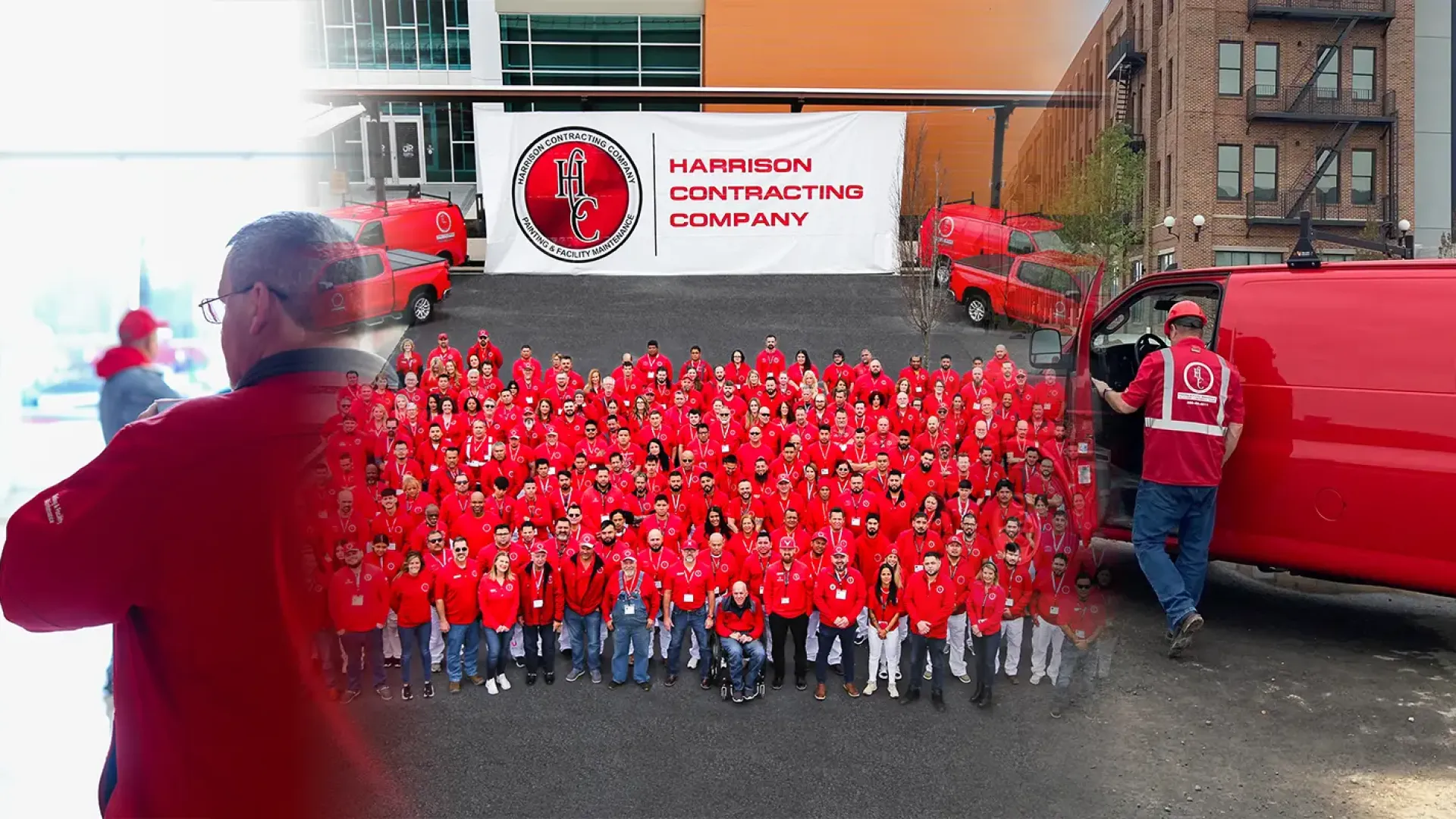 Large group of Harrison Contracting Company employees in red uniforms with branded vans and banner outdoors.