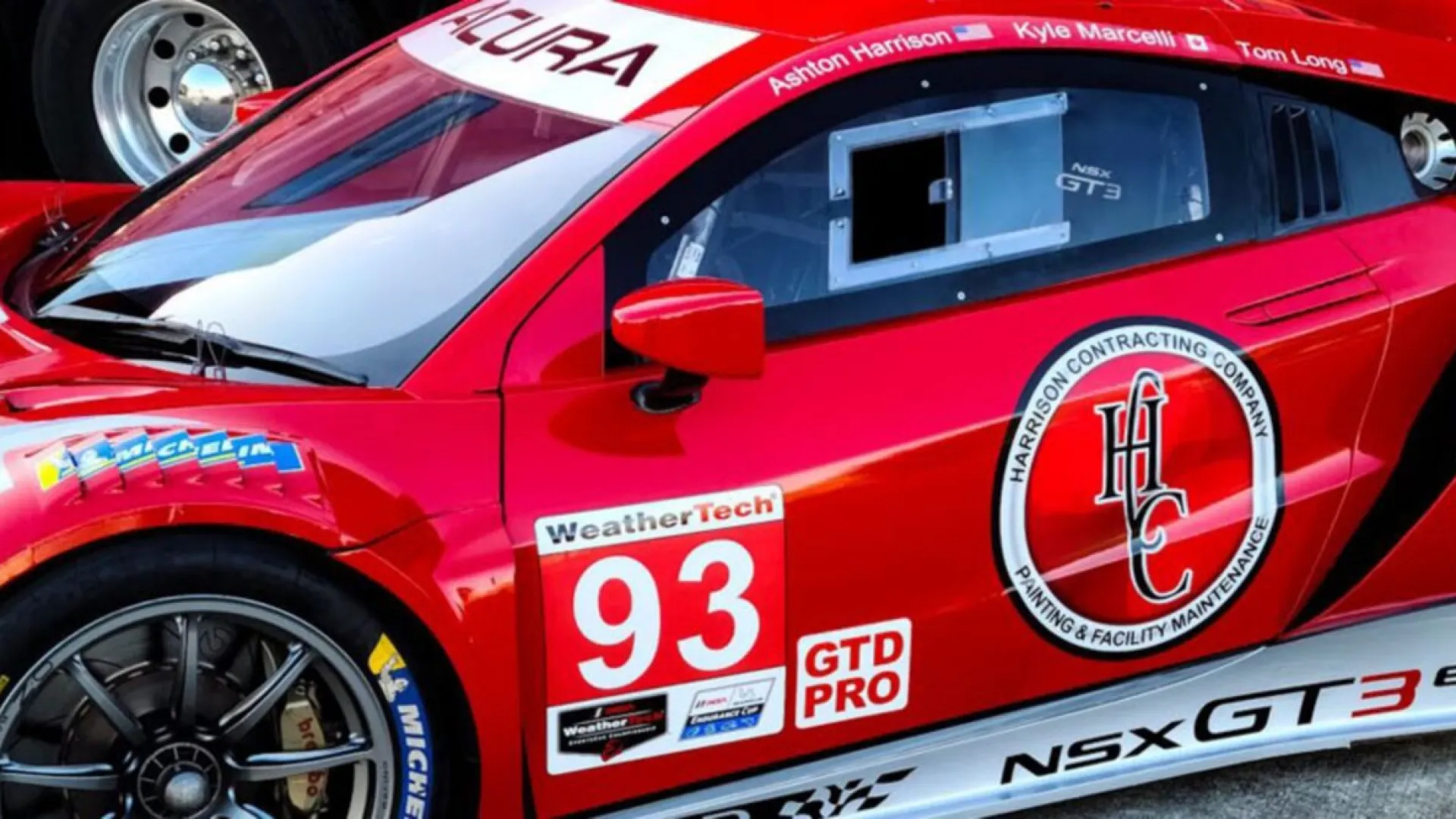 Red Acura NSX GT3 Evo 22 race car number 93 with sponsor logos and racing decals on trackside pavement.