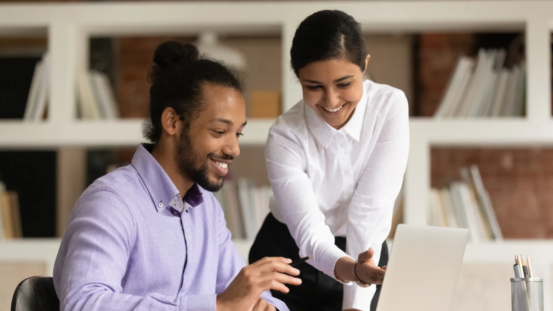 a man and a woman sitting at a table using a laptop