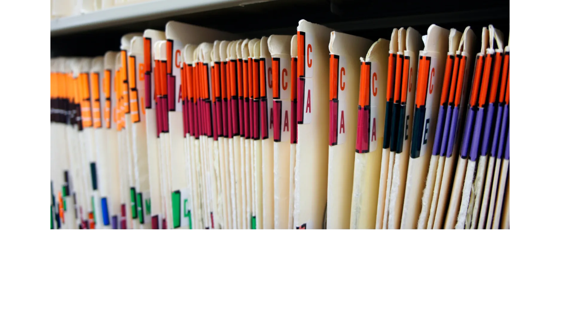 Close-up of organized medical or office files with colored tabs on a shelf.