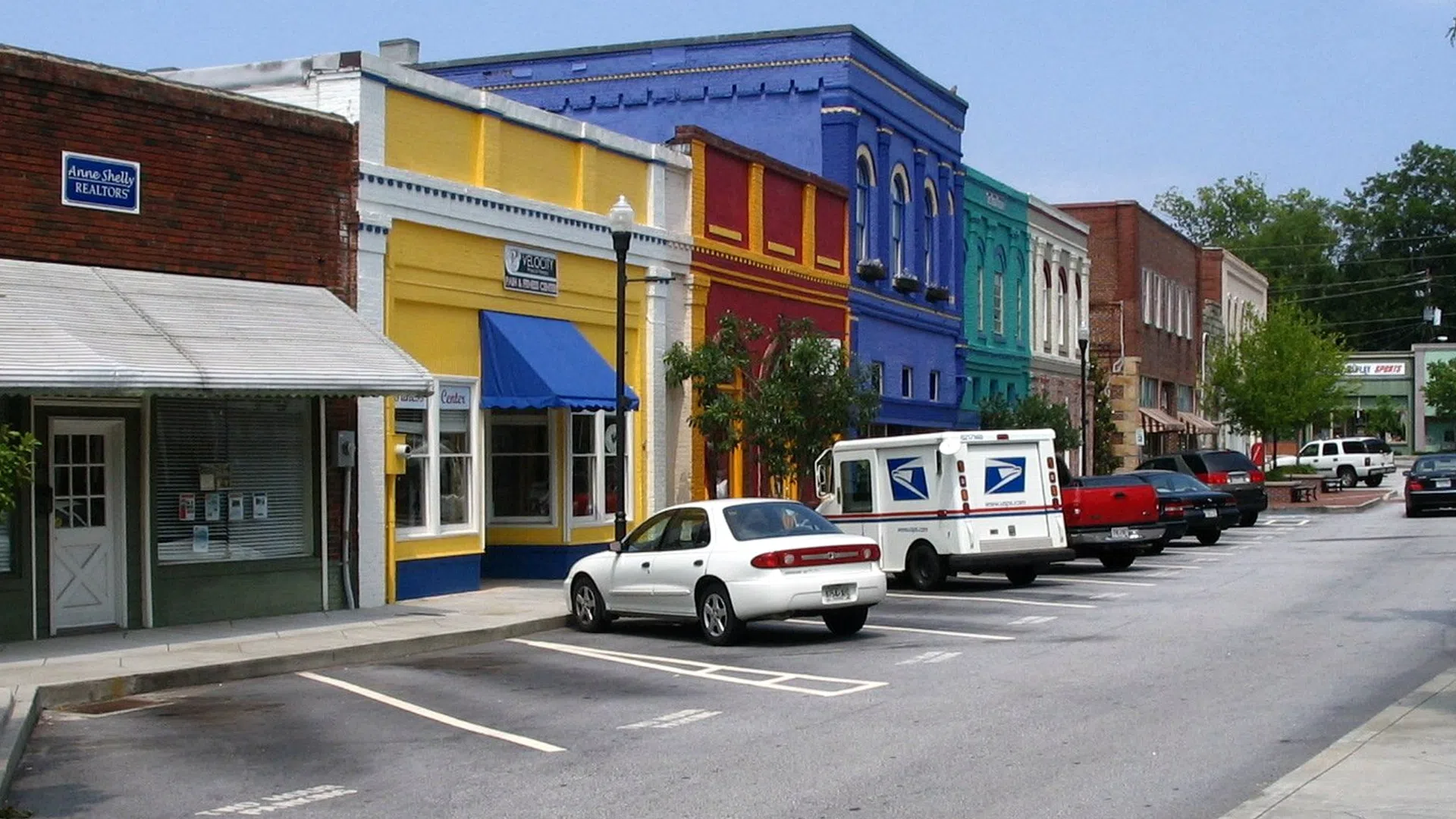 Small town main street with colorful historic buildings and parked cars under clear blue sky