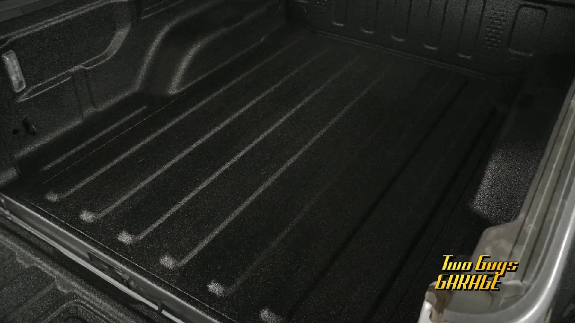 Close-up of a clean black truck bed liner with textured surface and grooves for durability and protection.