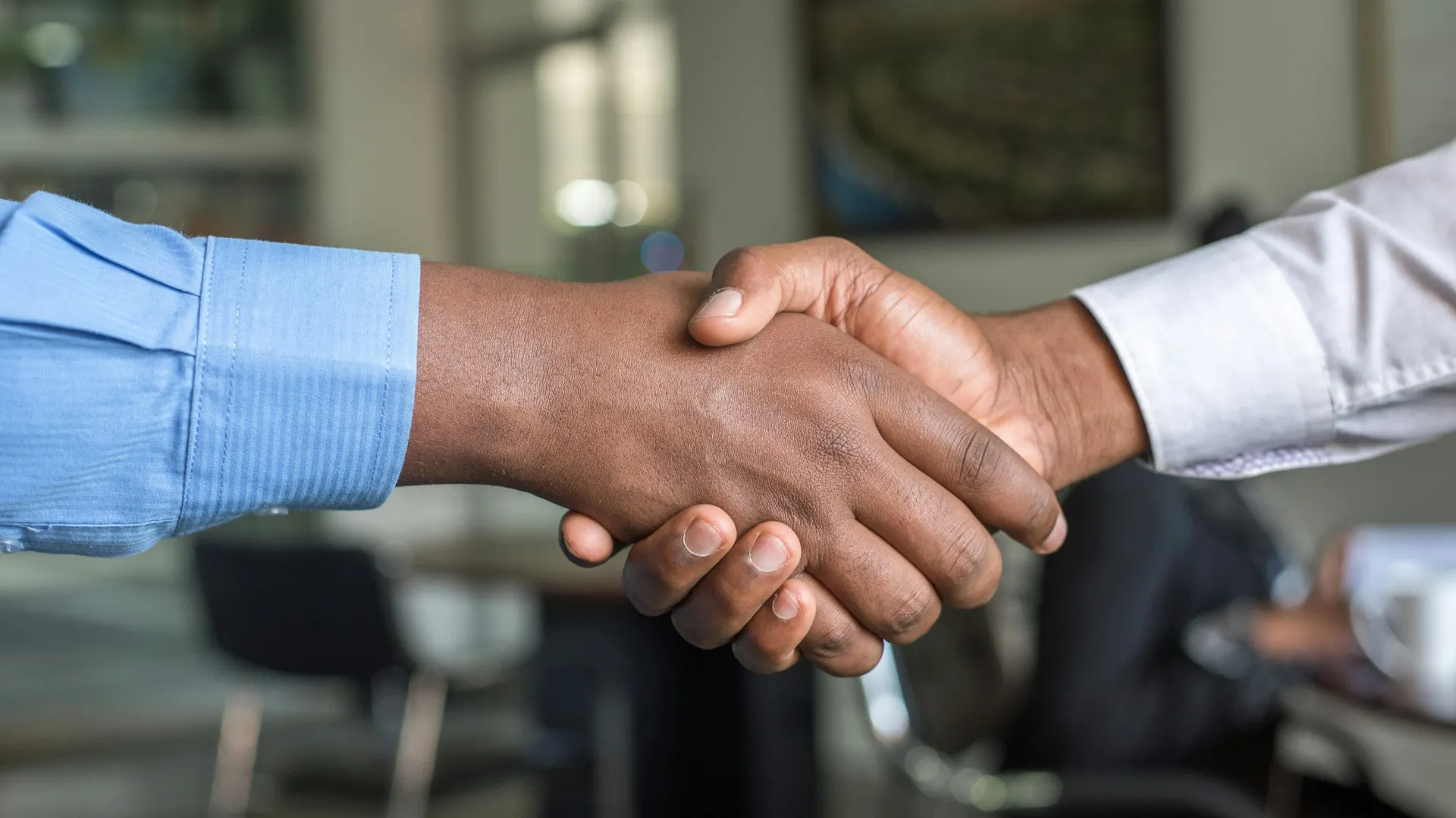 Two people shaking hands in a professional setting symbolizing agreement and partnership.