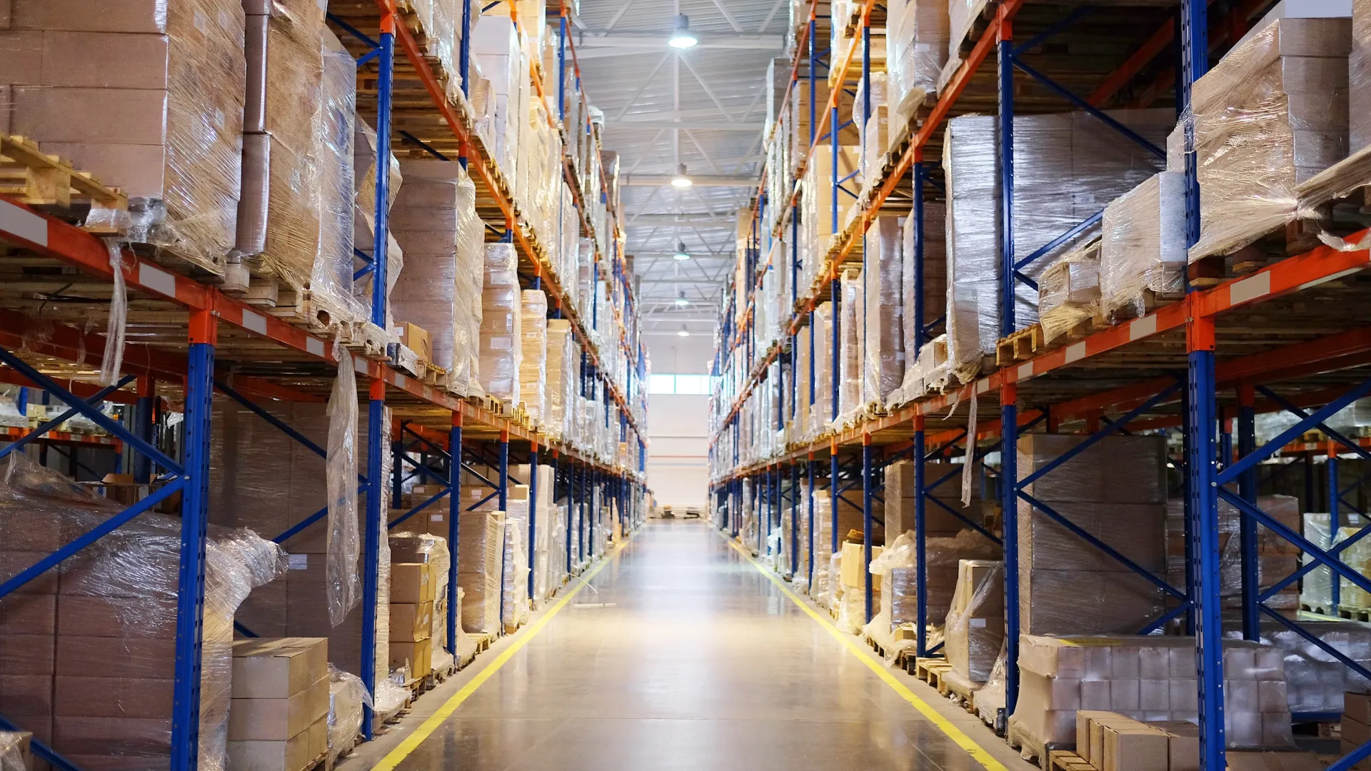 Inside a spacious warehouse with stacked shelves full of boxes and organized storage aisles.