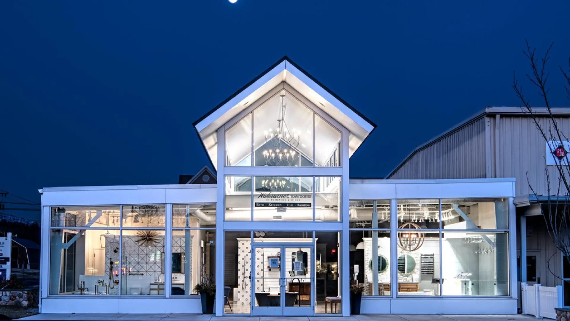 Modern building facade illuminated at night with large glass windows and a bright moon.