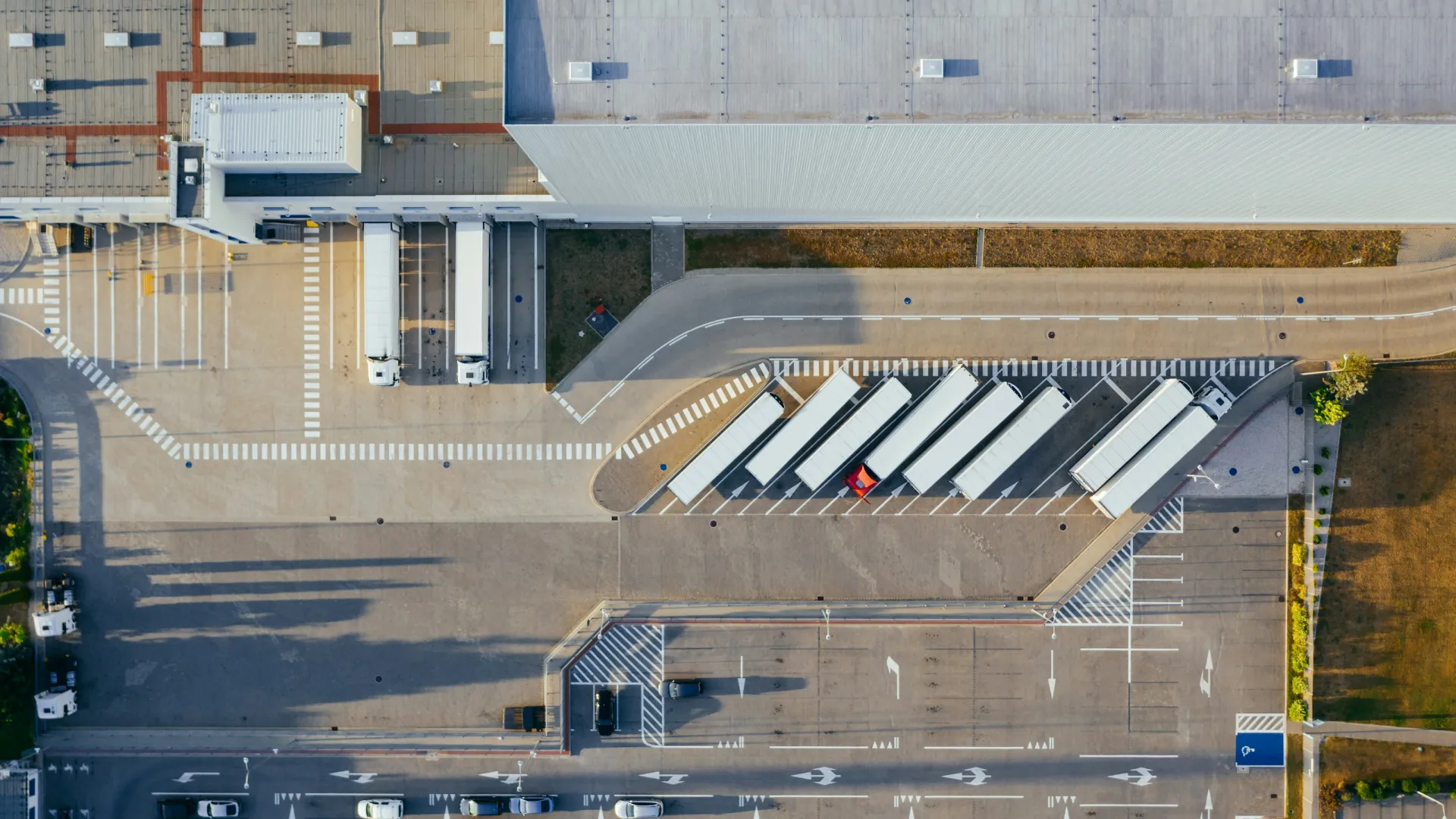 Aerial view of a logistics center with parked trucks and a spacious parking lot.