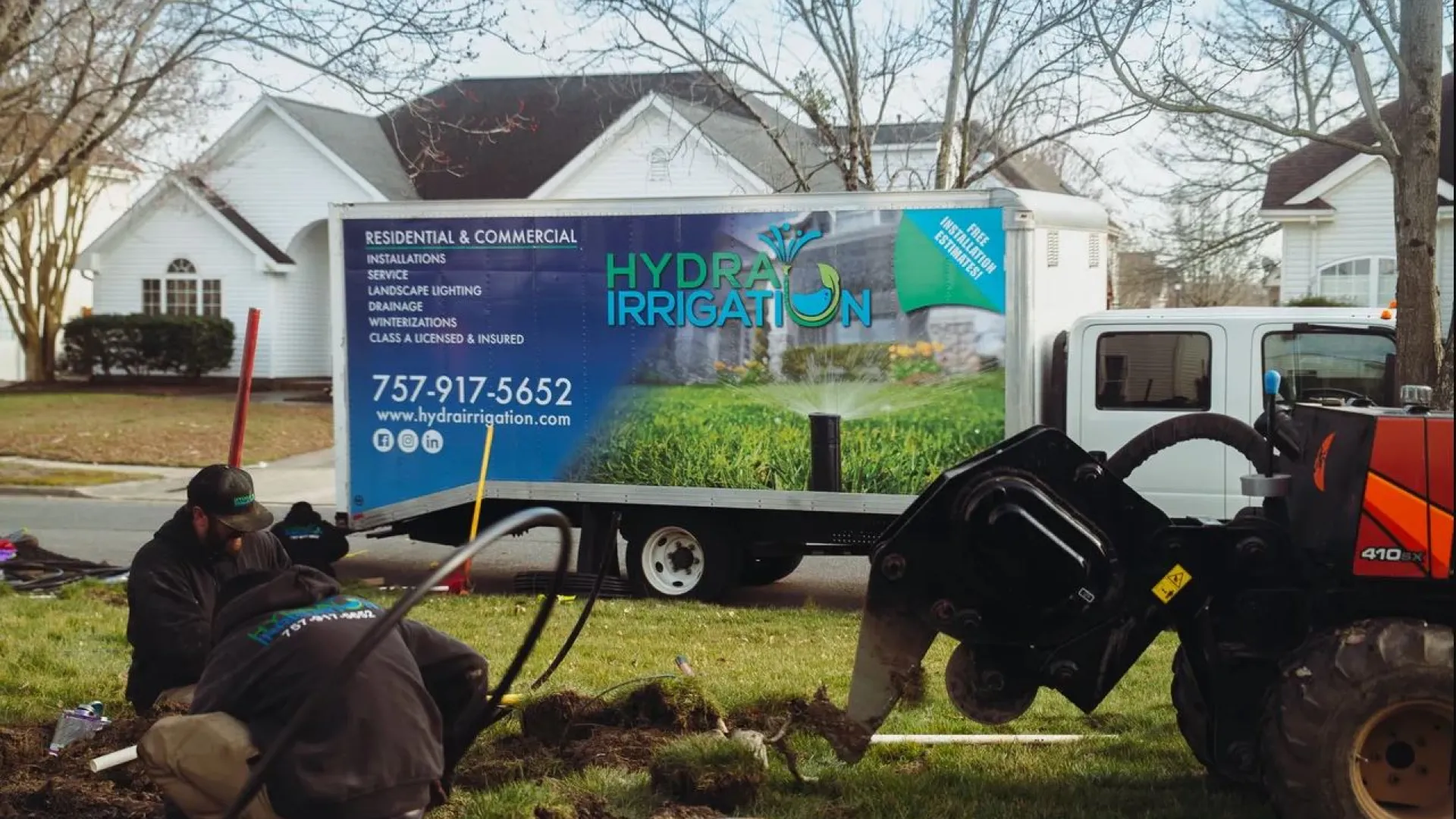 Workers installing irrigation system near a truck featuring Hydrat Irrigation branding.