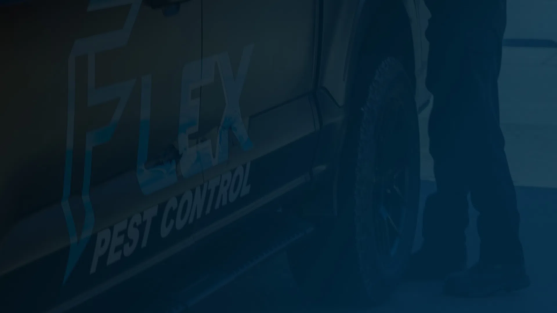 Close-up of a Flex Pest Control vehicle with a technician standing beside its tire in daylight.