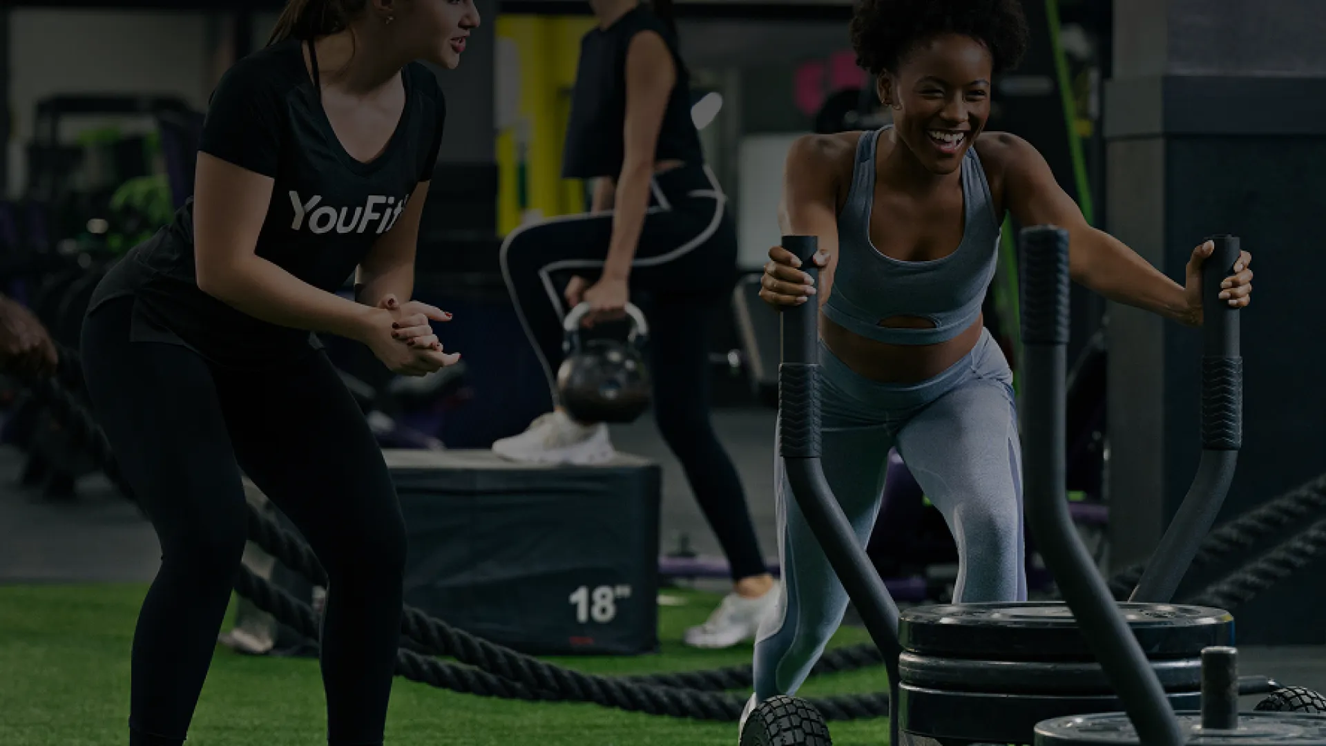 Group of diverse people working out with battle ropes in a modern gym setting, focused on strength training.