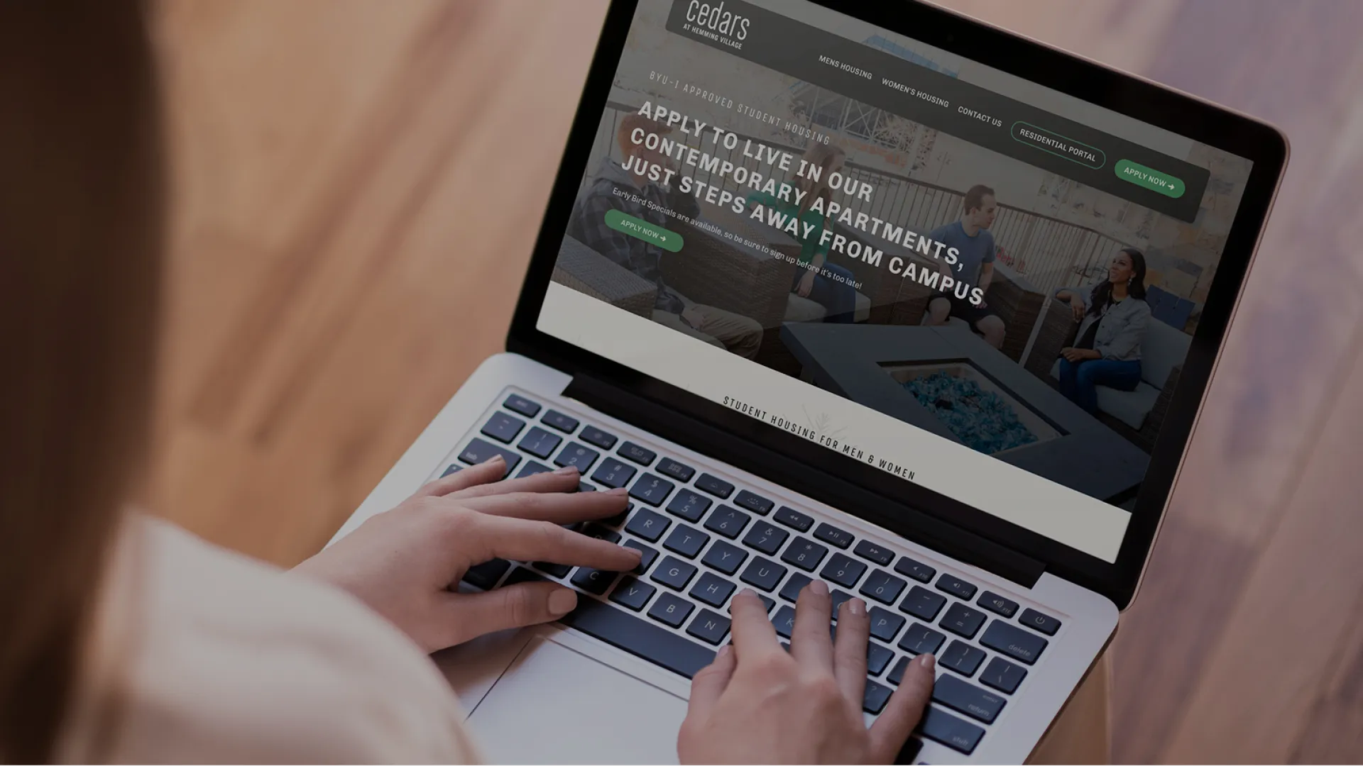 Person browsing apartment rental website on laptop, focusing on contemporary living near campus options.