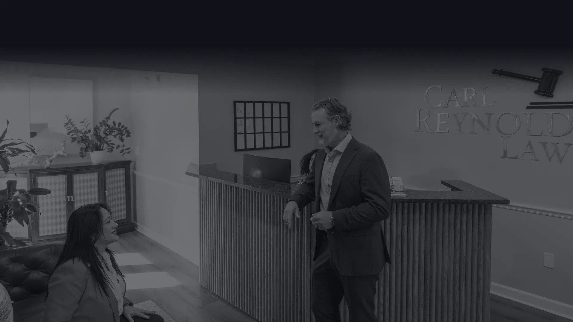 Professional lawyer consulting a client in a modern law office reception area with wooden floors and plants