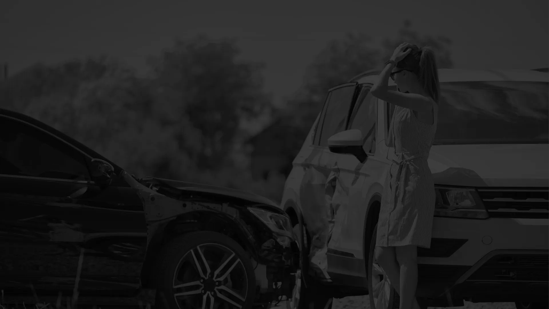 Woman standing beside two damaged cars after a collision on a sunny day in an outdoor setting.
