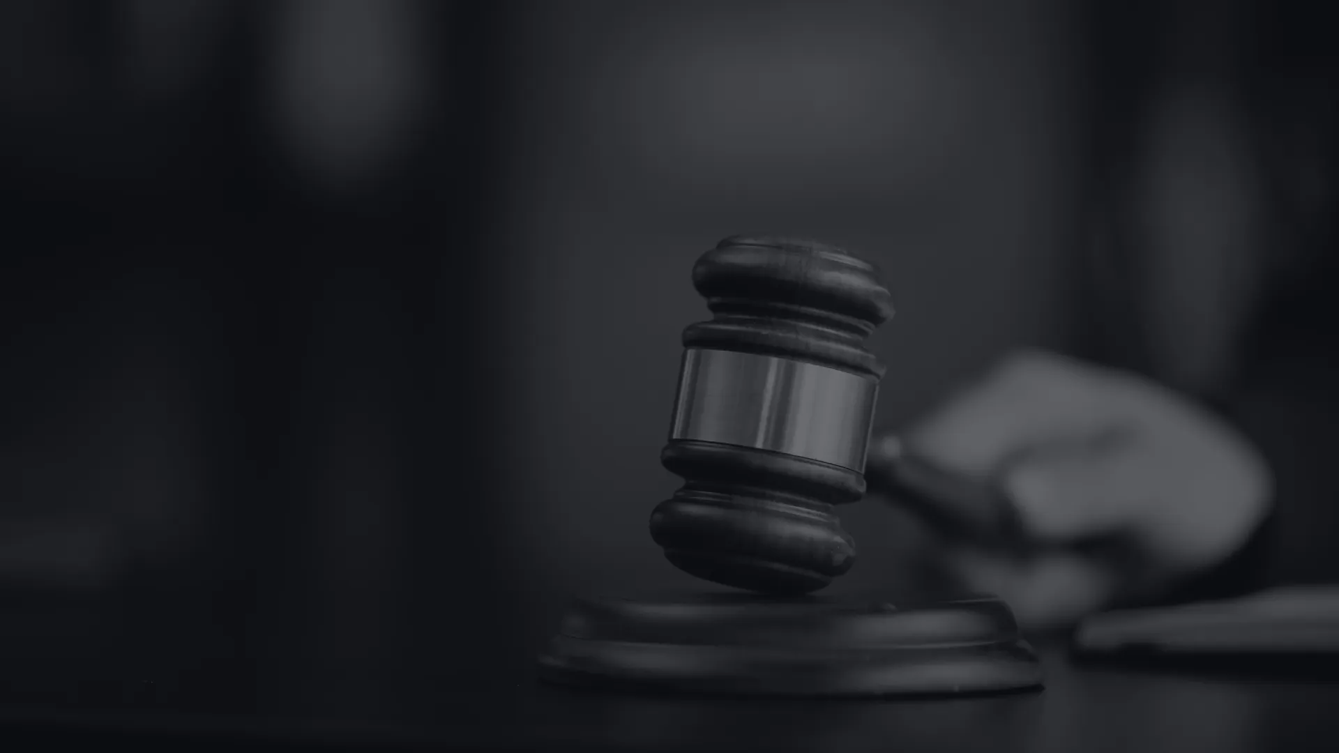 Judge's wooden gavel striking sounding block symbolizing justice and law in courtroom setting.