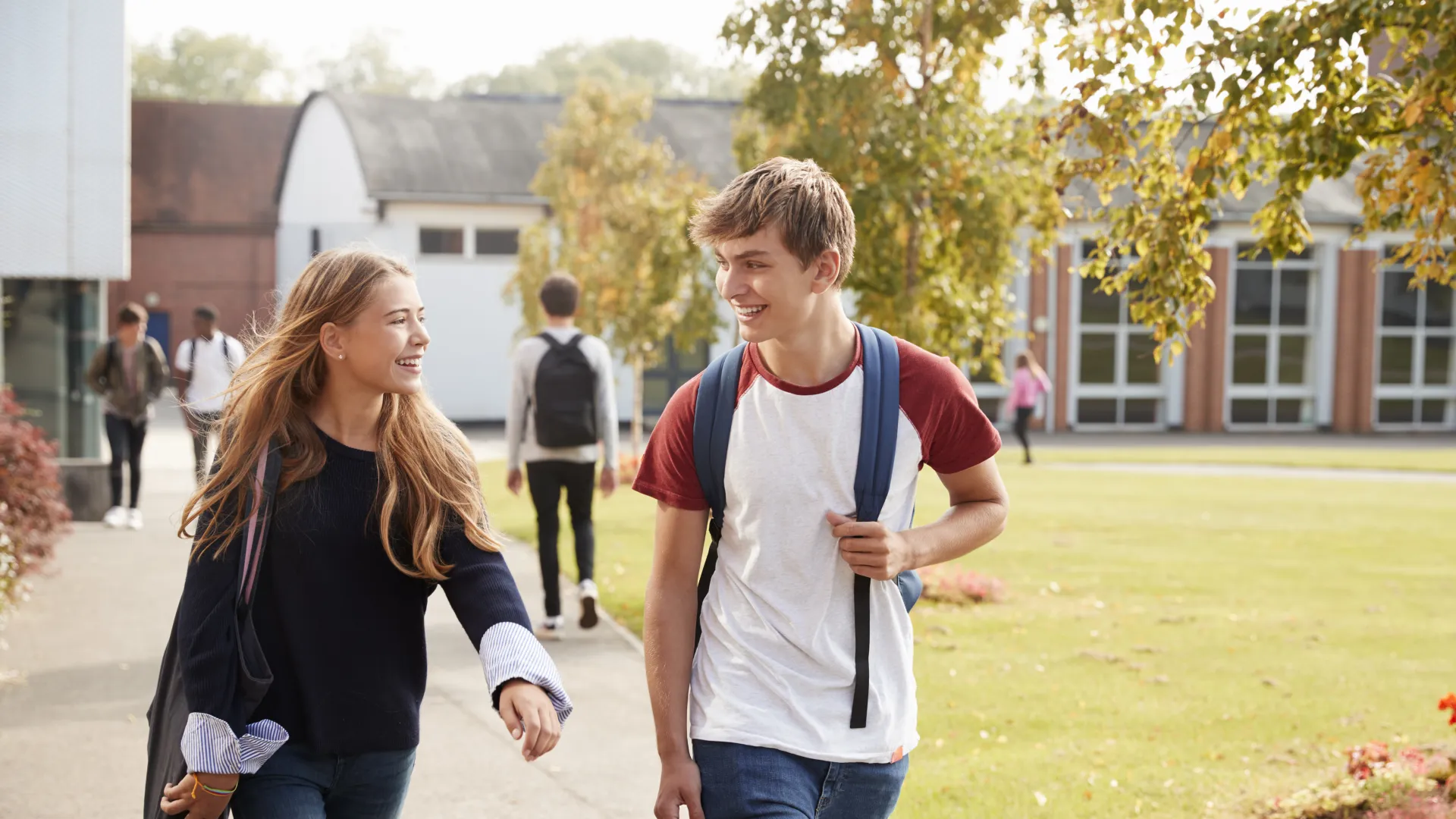 a boy and girl walking on a sidewalk