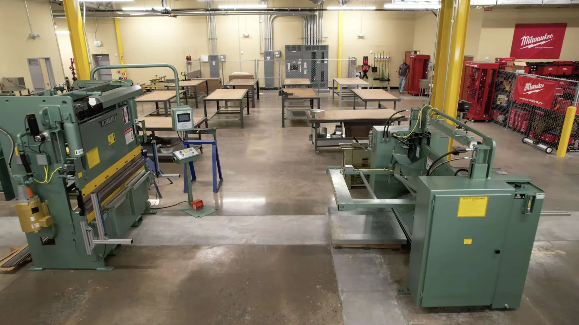 Industrial workshop with metalworking machines and workbenches organized in a spacious factory setting.