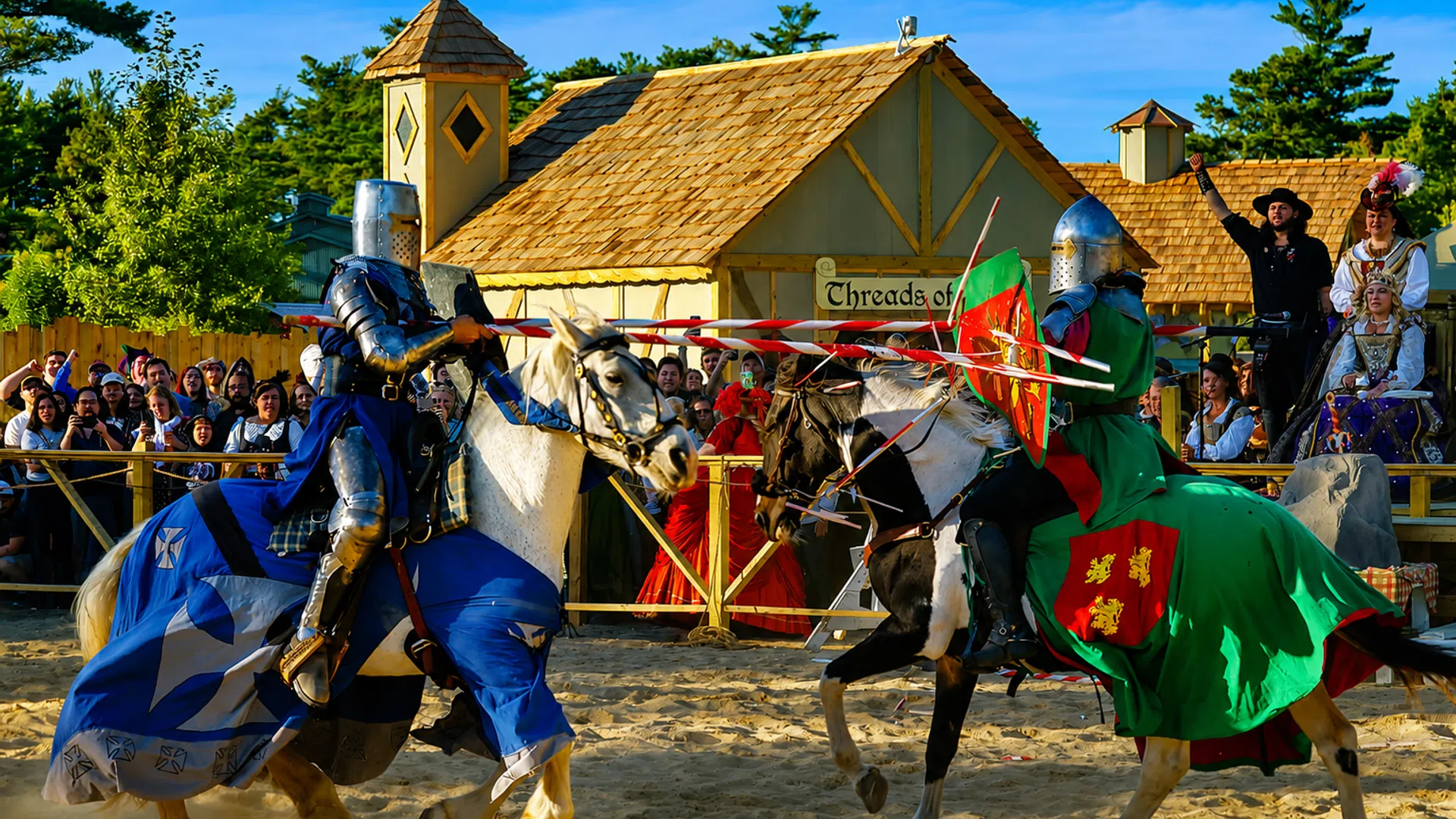 Two knights in armor jousting on horseback during a medieval festival with spectators and period buildings.