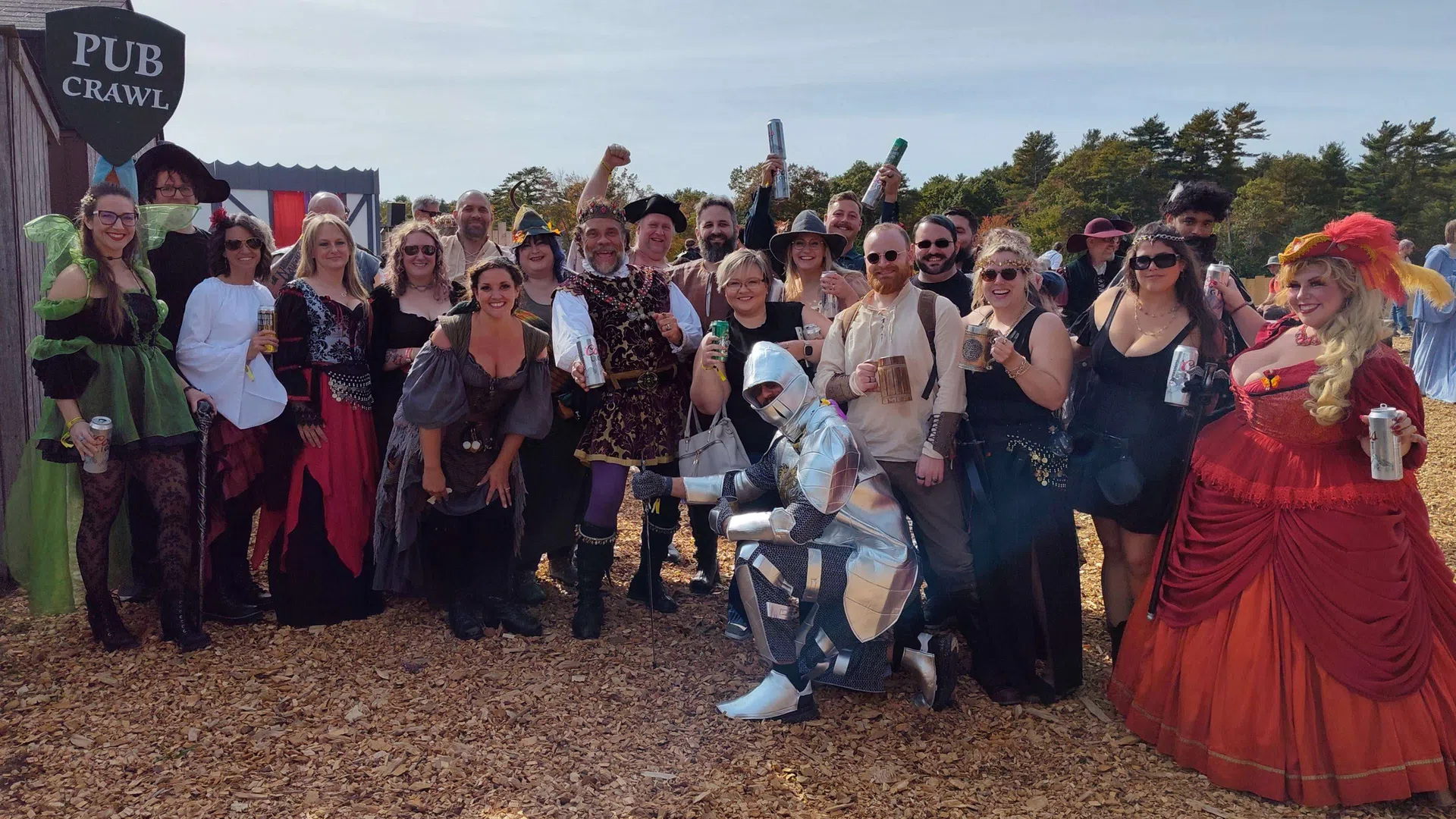 Group of people in medieval costumes enjoying a pub crawl outdoors with drinks and festive atmosphere