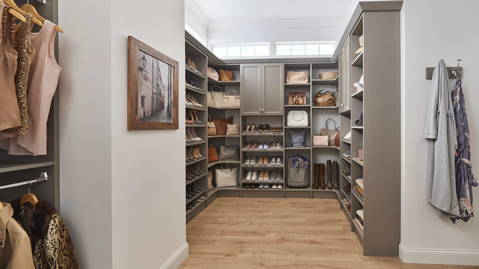 Organized walk-in closet with shelves for shoes and handbags, hanging clothes, and natural light from windows.
