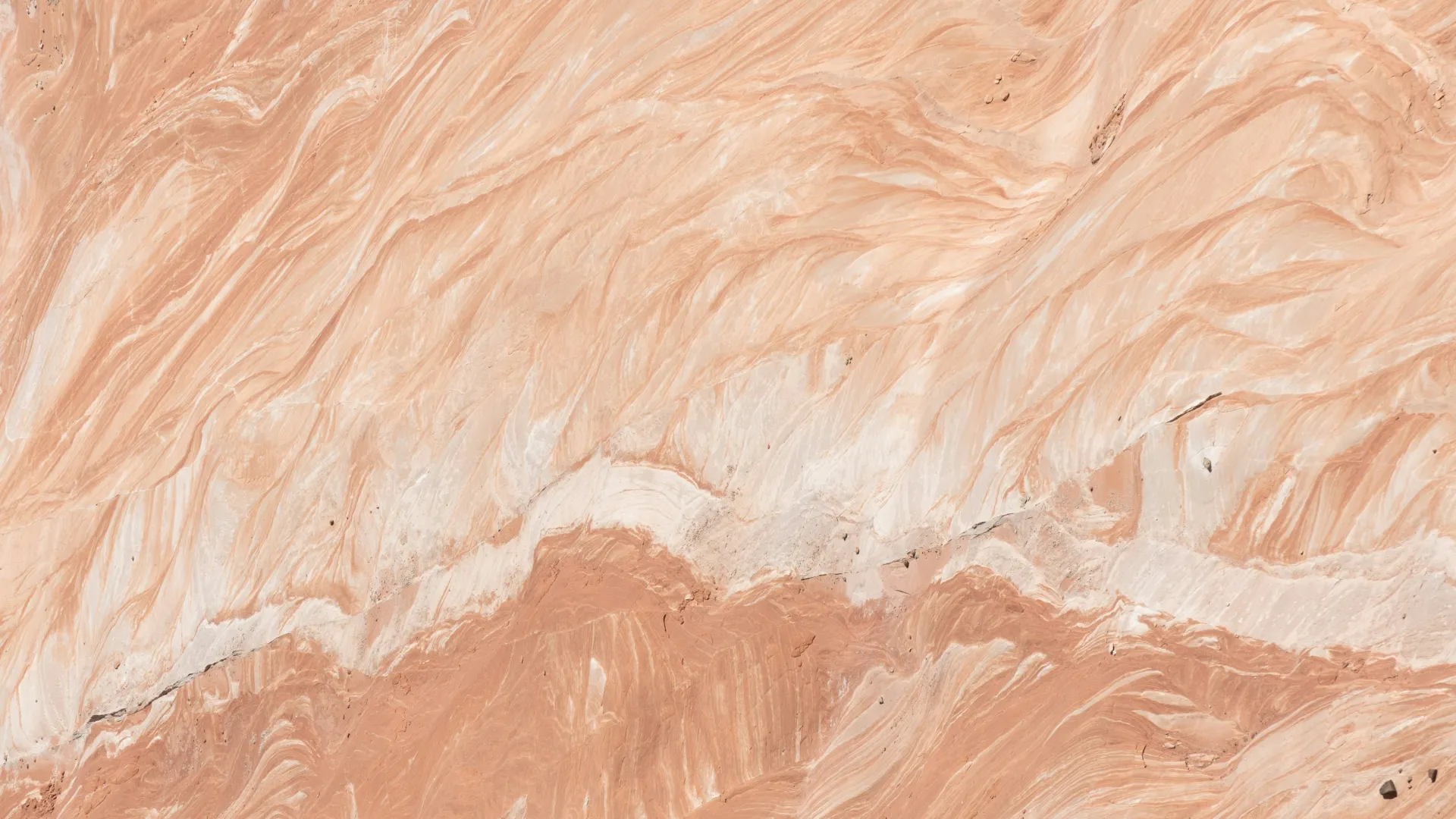 Close-up of natural peach and beige marble surface with intricate swirling veins and textures.