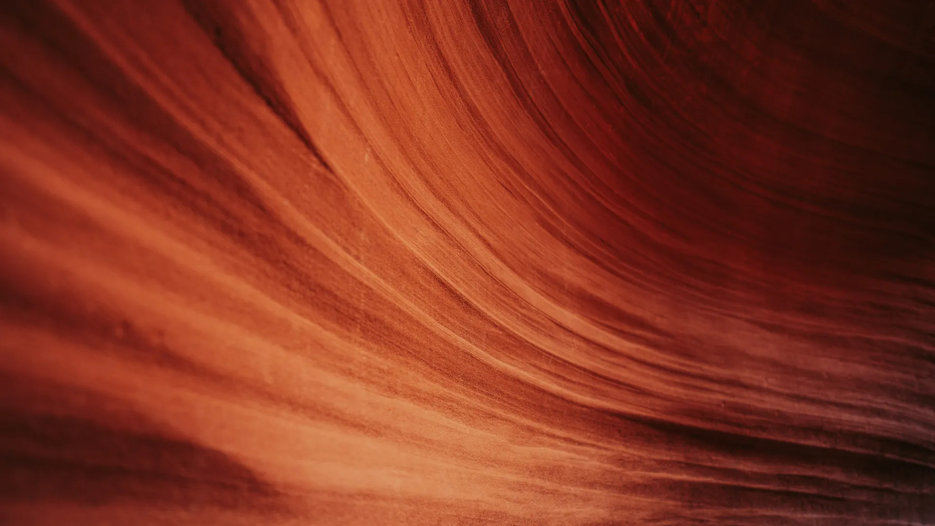 Smooth, flowing red sandstone layers with natural curved patterns in a canyon wall.