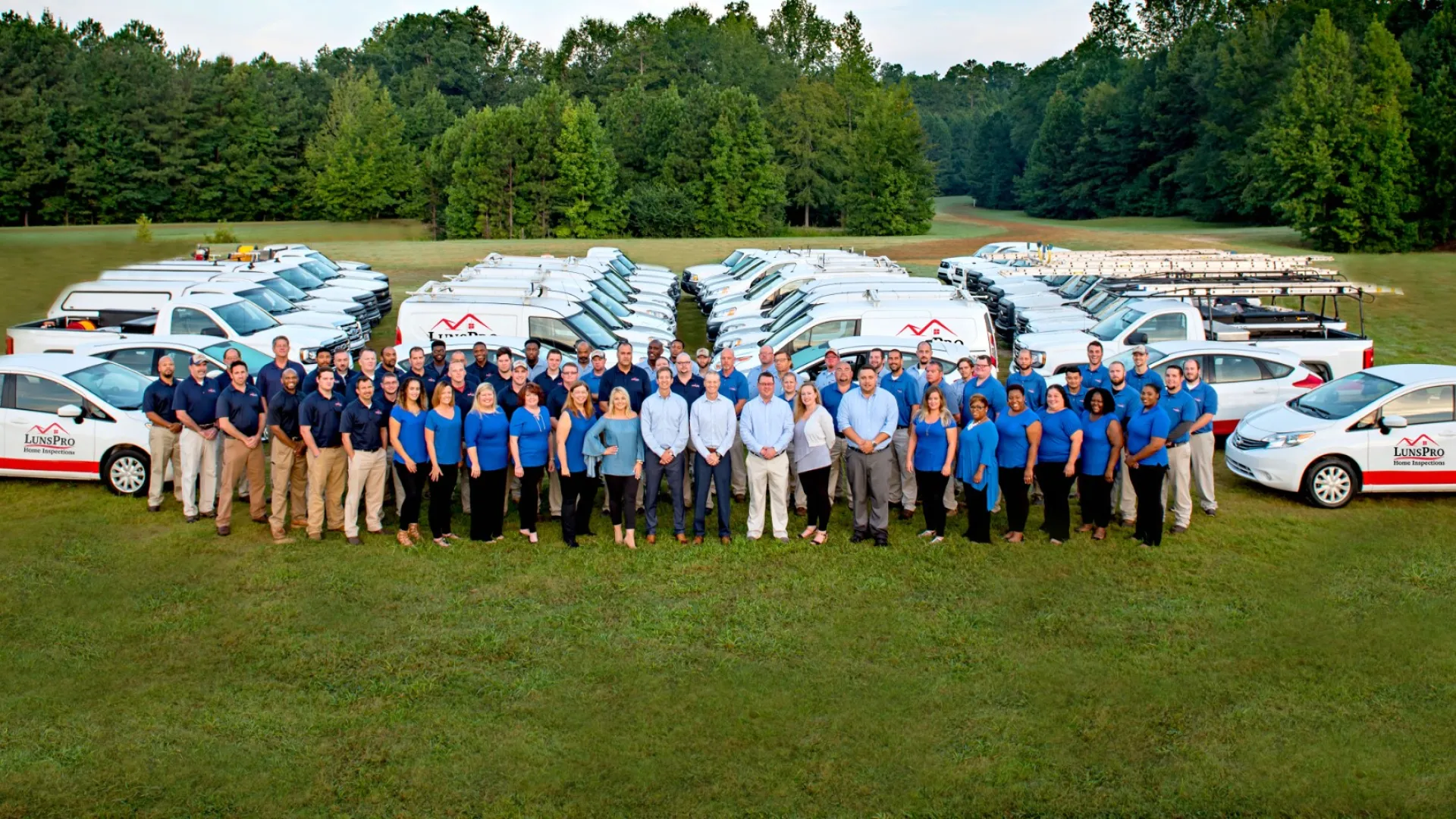 a group of people posing for a photo with cars and trees in the background