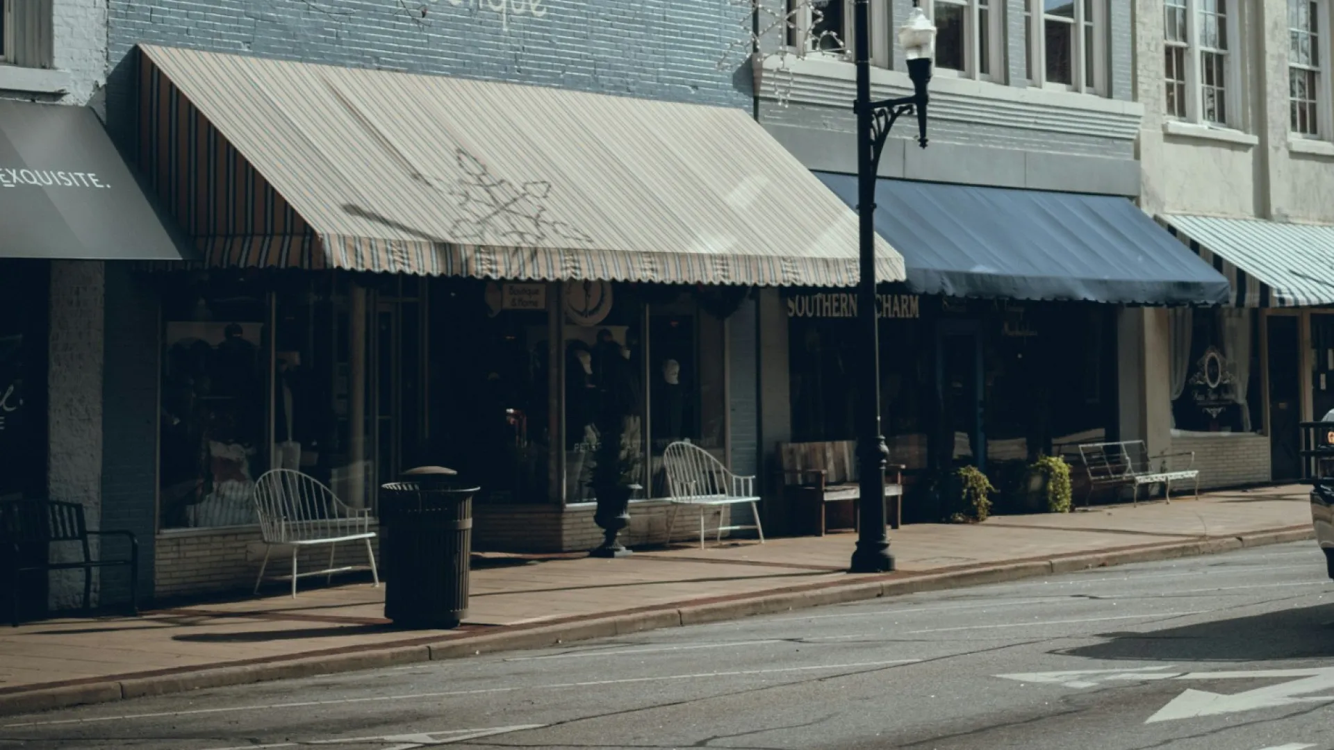 Historic downtown street with boutique shops and bare trees under a cloudy sky in autumn.